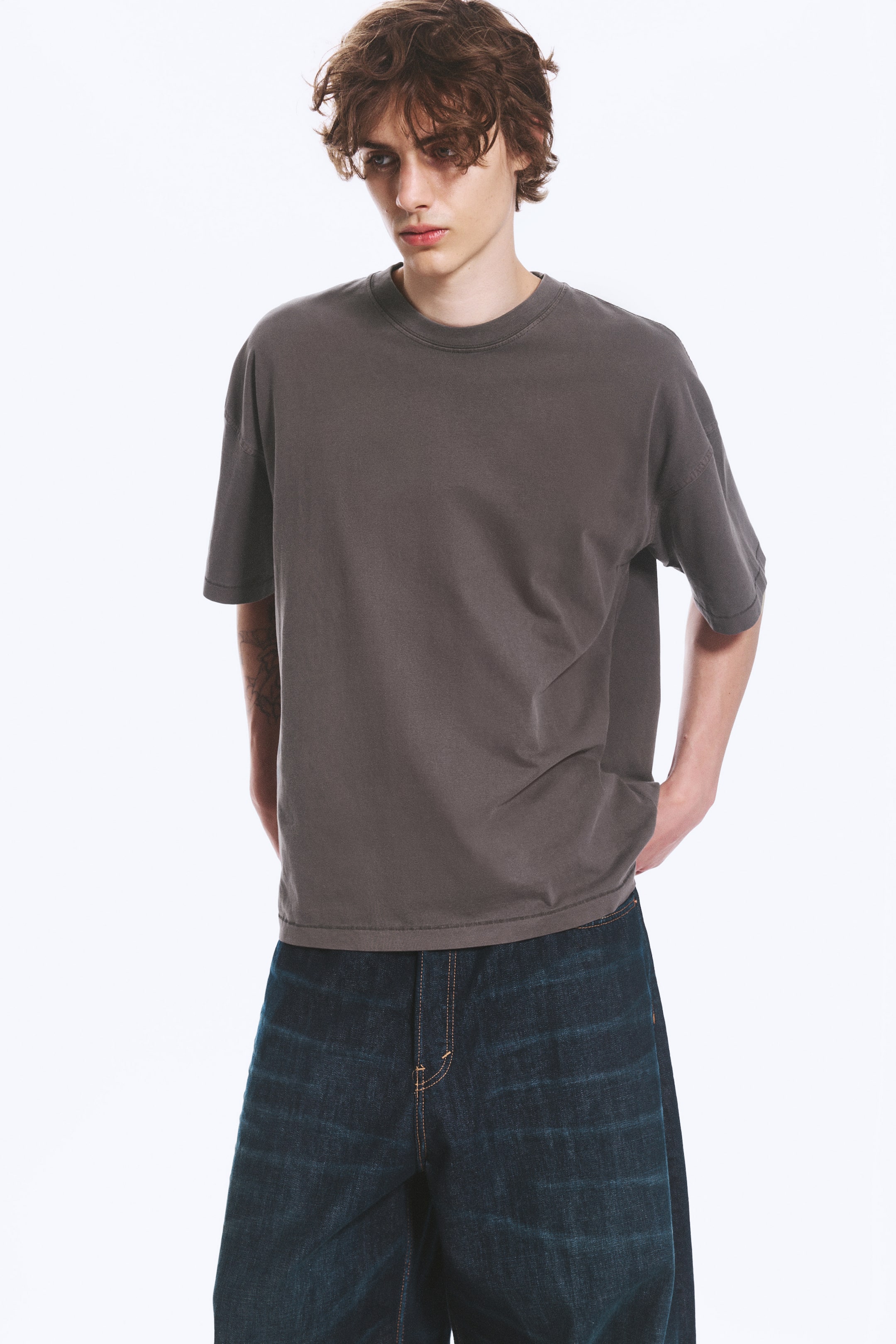Grotere afbeelding bekijken: Een donkergrijs T-shirt met korte mouwen, voorzien van een ronde hals en een ontspannen, oversized pasvorm. Het heeft een licht vervaagde uitstraling en een rechte zoom.