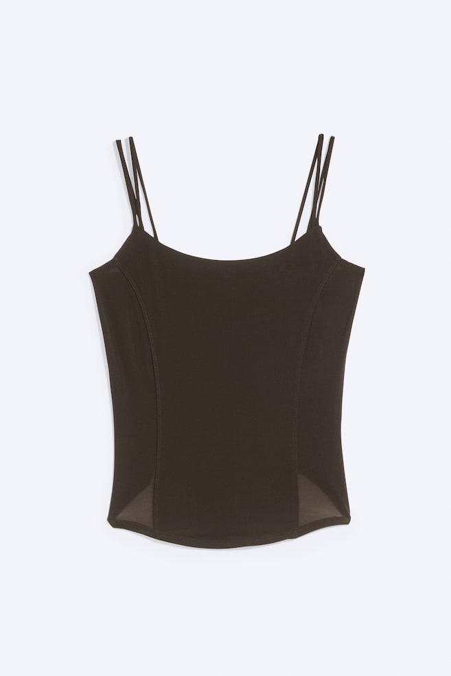 Ein dunkelbraunes Camisole-Top ist frontal zu sehen und verfügt über doppelte Spaghettiträger sowie einen Rundhalsausschnitt. Das taillierte Design zeigt vertikal geschwungene Nahtlinien auf dem Vorderteil und transparente, dreieckige Mesh-Einsätze an den unteren Ecken des Saums. - 1