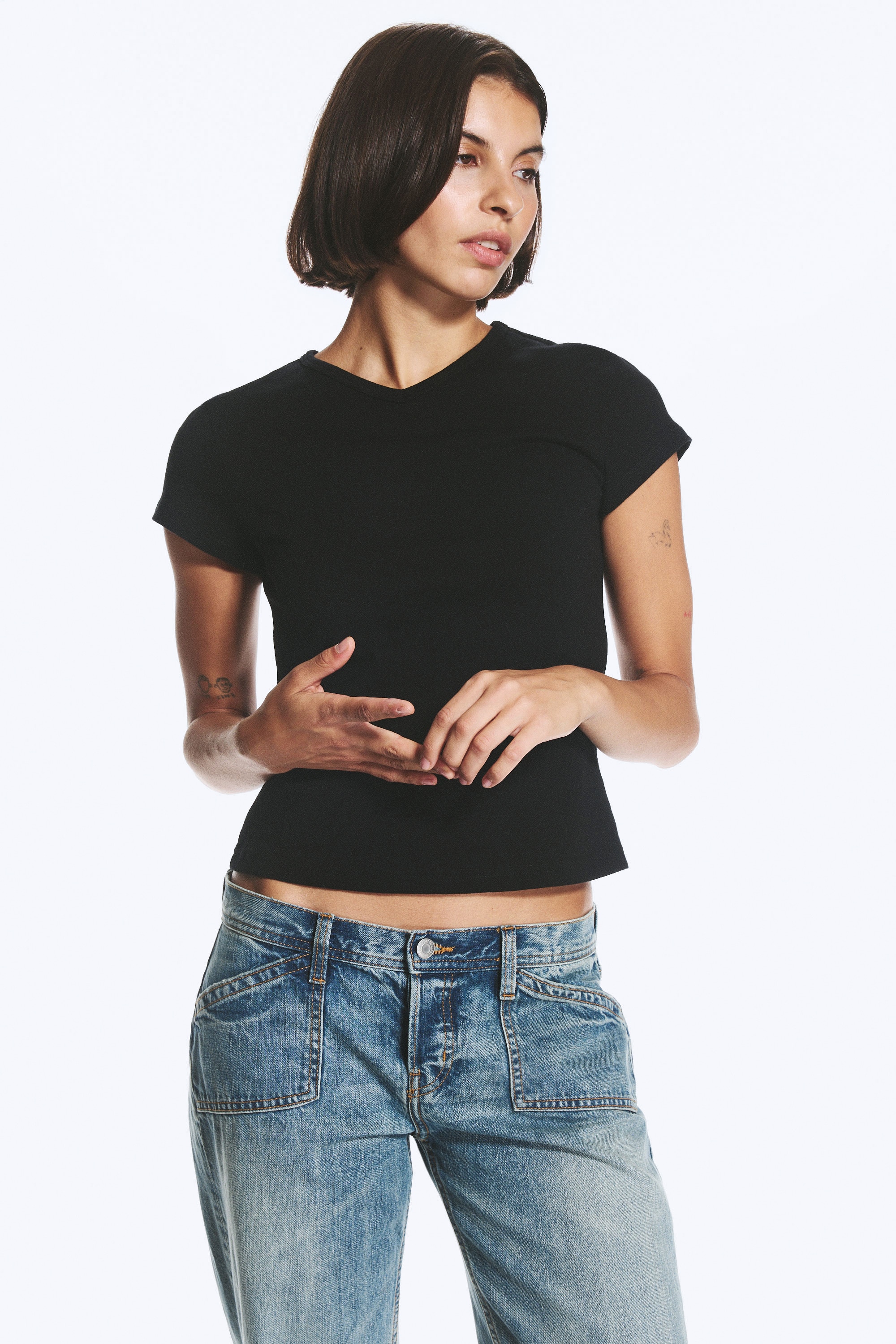 Ein schwarzes Slim-Fit-T-Shirt ist von vorne zu sehen, mit V-Ausschnitt, kurzen Ãrmeln und einem leicht verkÃ¼rzten, geraden Saum.