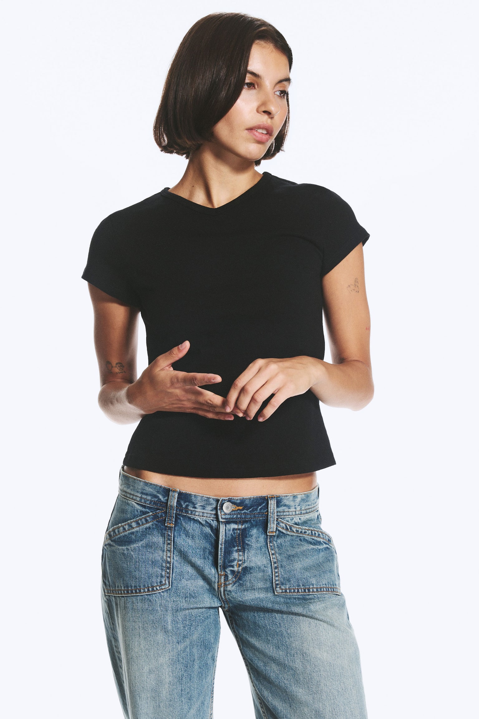 Un tricou negru slim-fit este prezentat din faÈÄ, având decolteu în V, mâneci scurte Èi un tiv drept, uÈor scurtat. - 1