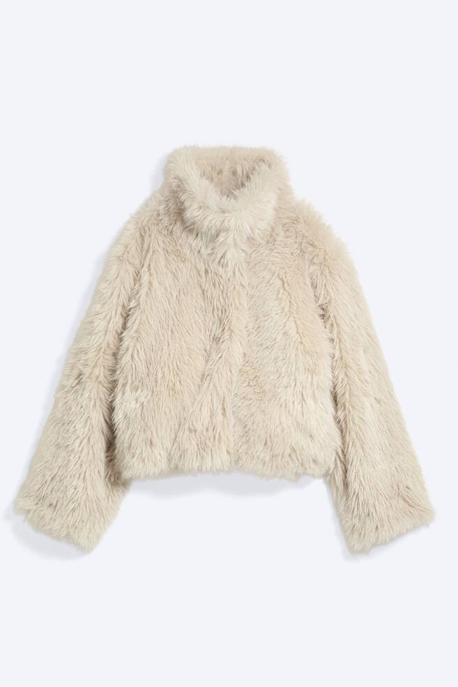 En lys beige jakke i imiteret pels vender frontalt og har en hÃ¸j, blÃ¸d krave samt lange, klokkeformede Ã¦rmer. Jakken fremstÃ¥r med en blÃ¸d, fluffy tekstur og en kort, cropped kant samt skjult lukning foran. - 1