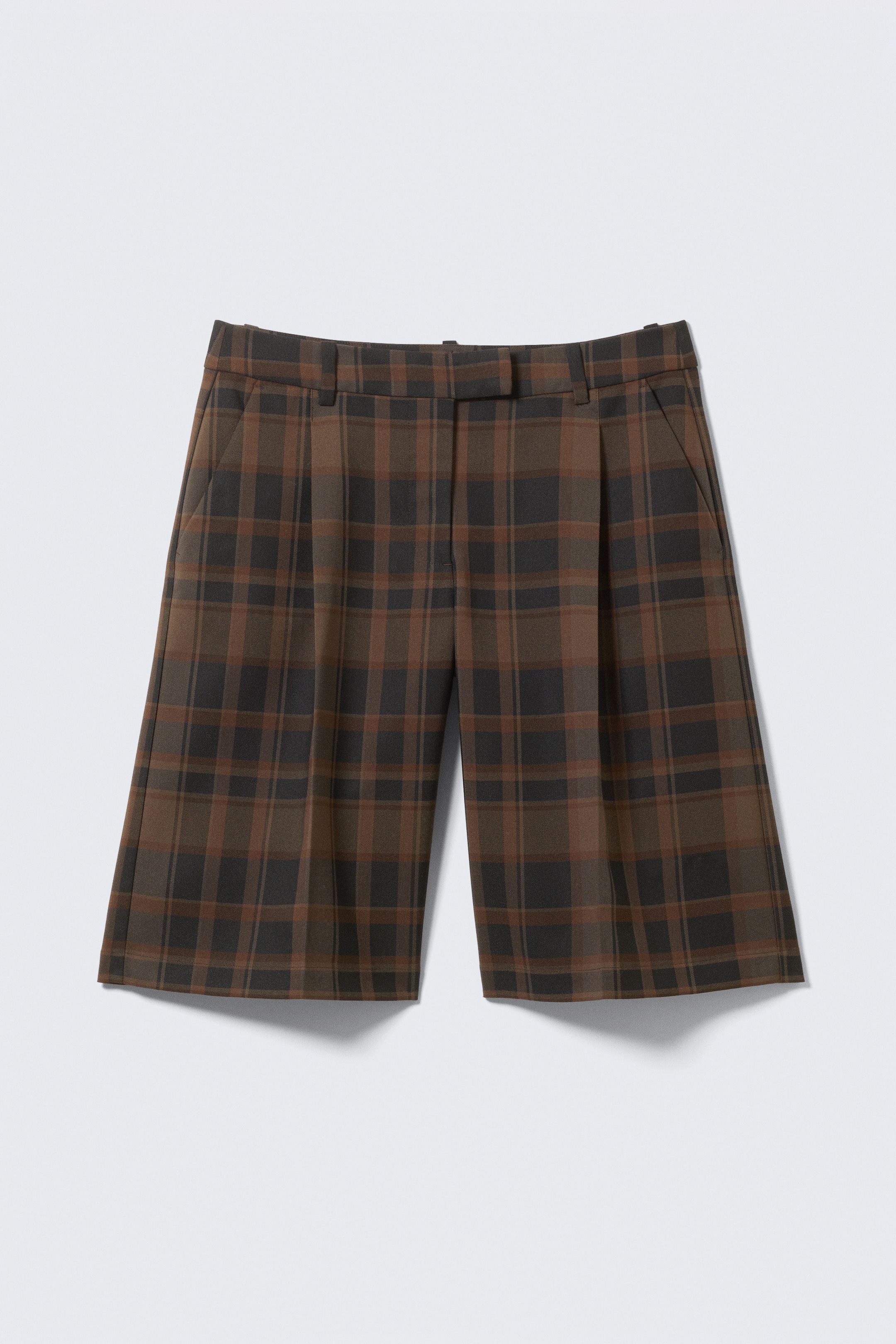 Visa större bild: Ett par knälånga kostymshorts, FRONT, visar ett brunt och svart rutmönster. De har frampressveck, bälteshällor och sidofickor, och visar en skräddarsydd silhuett med subtil volym genom benet.