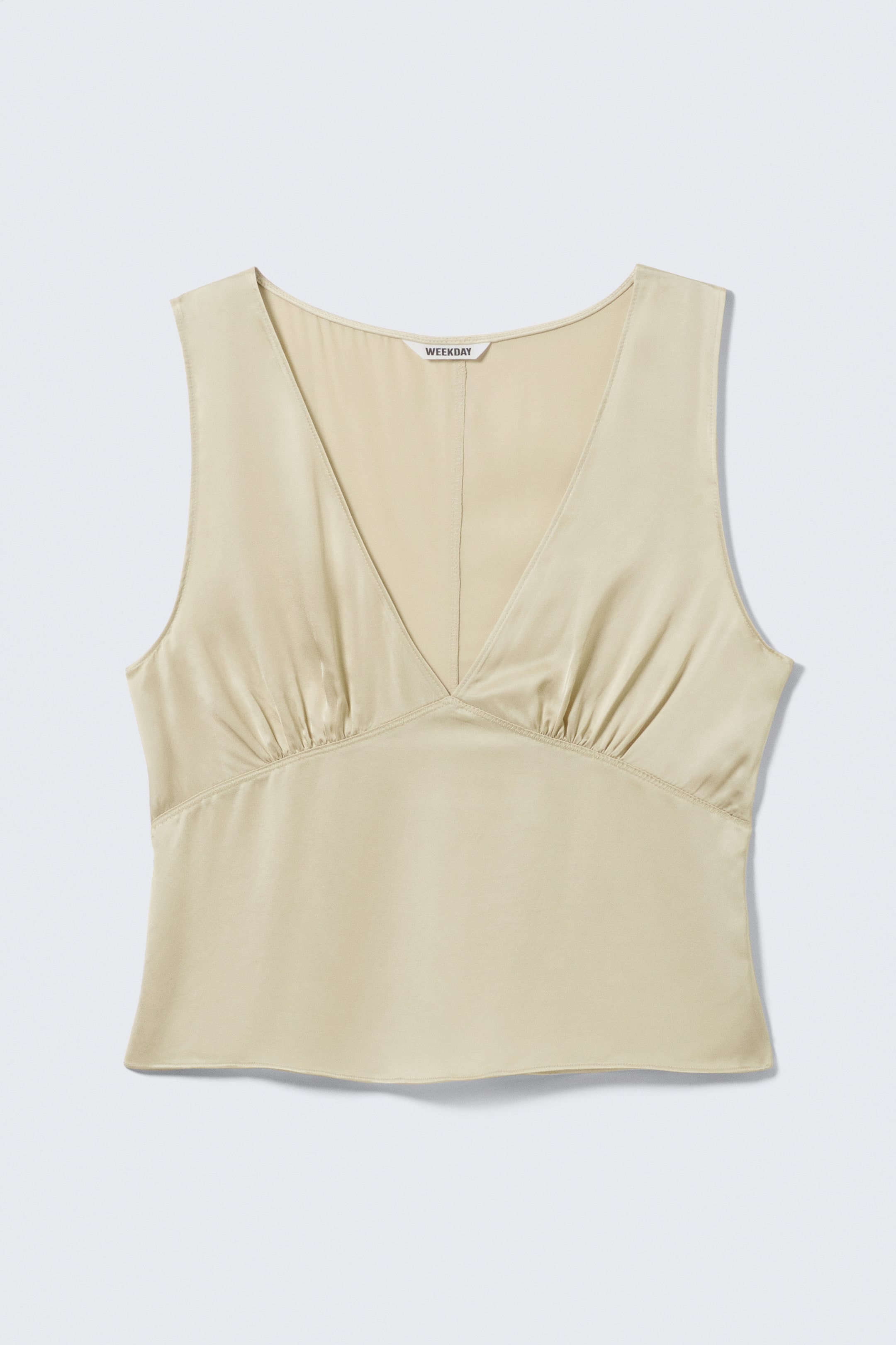 Zobacz większy obraz: Jasny beżowy top bez rękawów prezentuje się jako FRONT, z dekoltem w serek i subtelnym połyskiem. Posiada poziomy szew poniżej linii biustu z marszczeniami po obu stronach oraz szew na środku przodu.