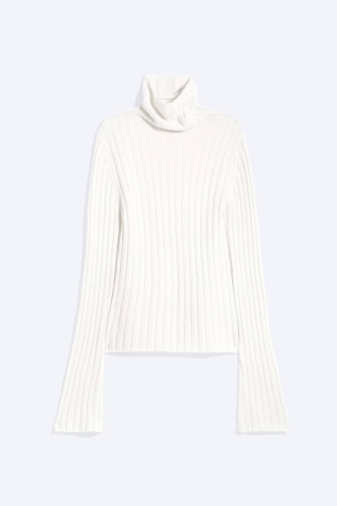 A white ribbed knit roll neck sweater is shown front-facing, featuring a folded roll neck and a vertical ribbed texture throughout. The long, straight sleeves extend well past the straight hemline. - 1
