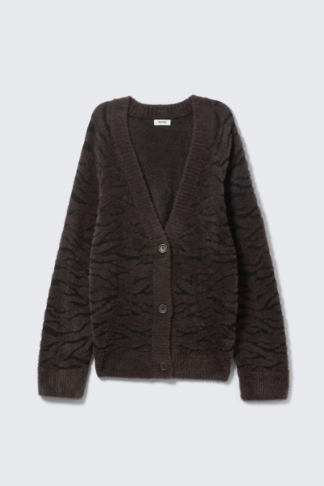 An oversized cardigan featuring a dark brown and black animal-stripe pattern is shown from the front. It features a deep V-neckline, a three-button front closure, dropped shoulders, and ribbed trims at the cuffs and hem. - 1