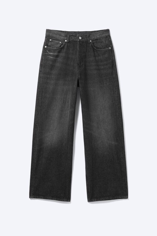A pair of dark grey, loose-fit jeans is displayed from the front, featuring a mid-rise waist, a classic five-pocket design with front rivets, and a button fastening at the waistband, indicating a button fly. The baggy legs exhibit a faded wash on the rigid denim. - 1