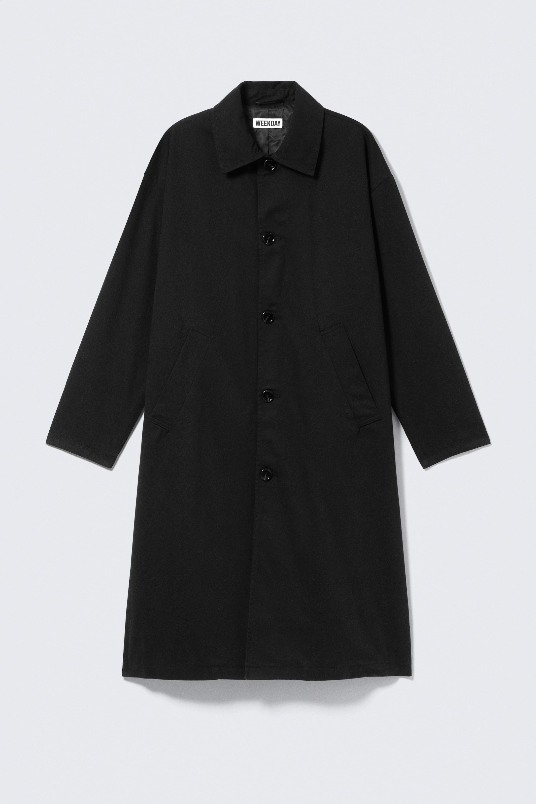 Agrandir l'image: Un manteau noir présente une fermeture frontale à boutons complets avec des boutons noirs, un col pointu et deux poches à rabat inclinées à l'avant. Il est doté de manches longues et d'une coupe décontractée à hauteur du genou.