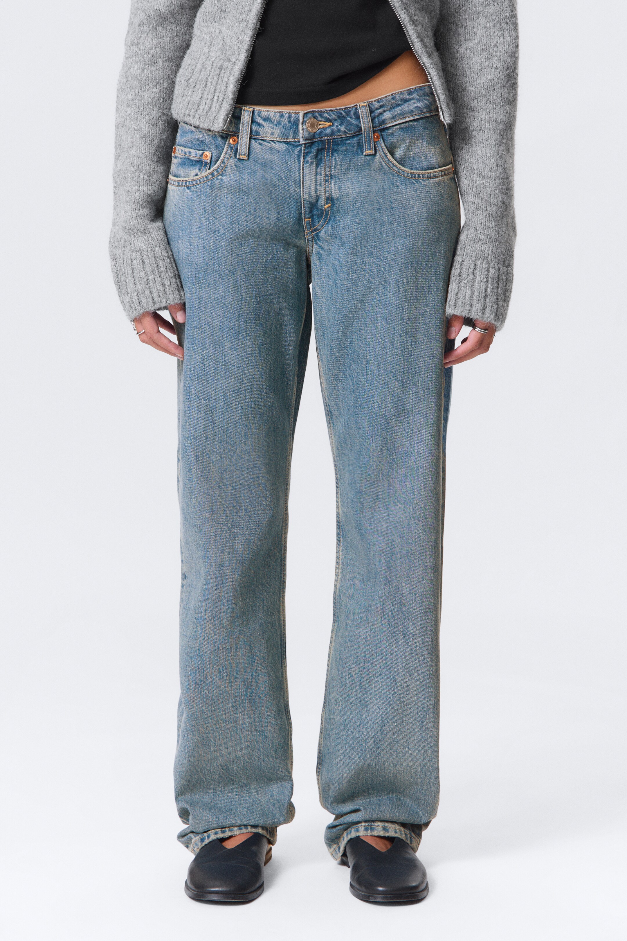 Agrandir l'image: Les jeans en denim délavé sont orientés vers l'avant, offrant une coupe droite et décontractée. Ils présentent une taille mi-haute avec une fermeture à bouton et à glissière, et des poches avant en biais visibles.