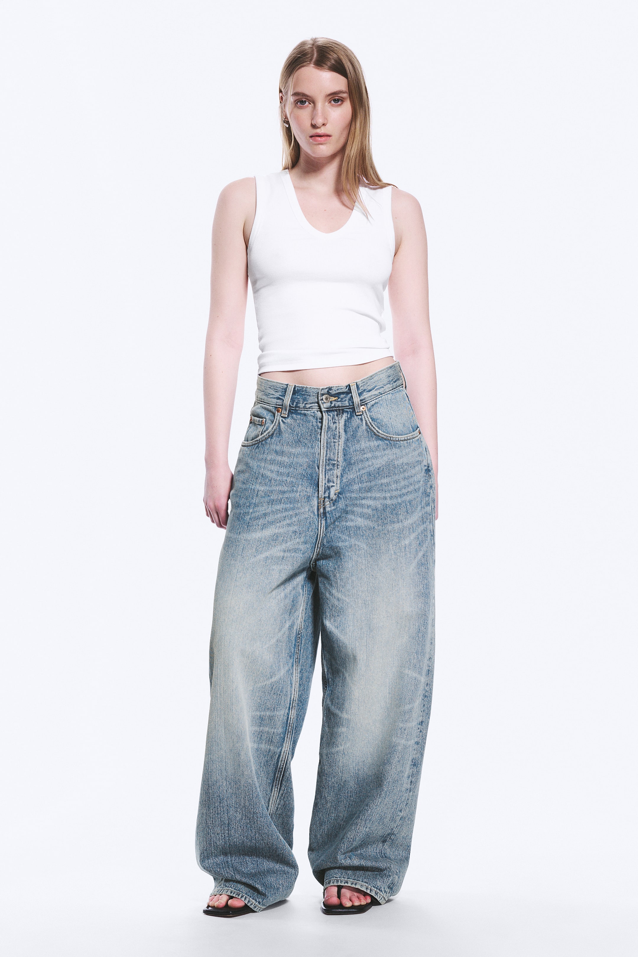 Visualizza immagine più grande: I jeans a gamba larga e larghi di colore azzurro chiaro presentano un lavaggio sbiadito e consumato, una vita alta e una chiusura con bottoni a vista. Appaiono oversize e con una vestibilità ampia lungo le gambe.