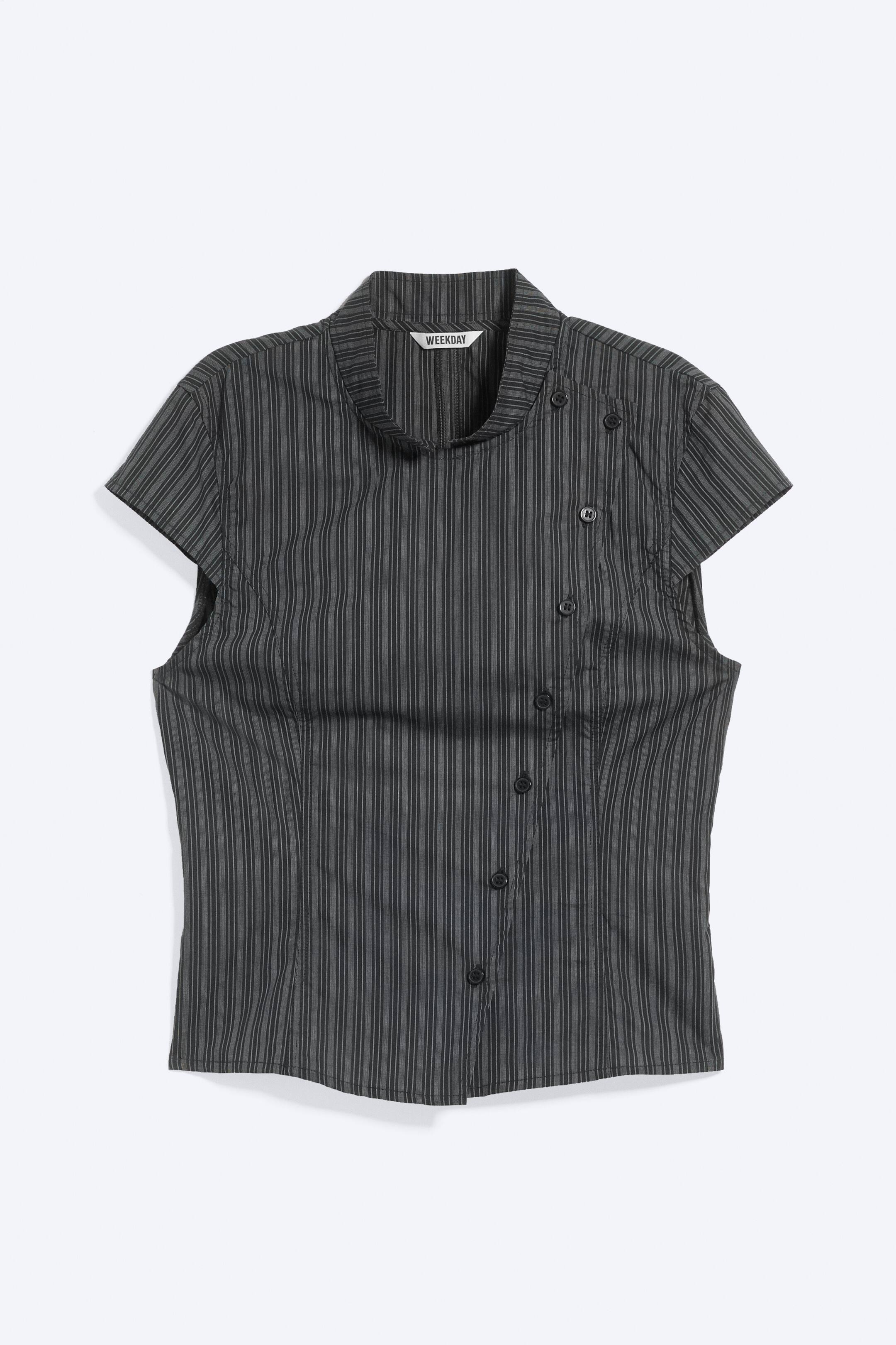 Agrandir l'image: Un haut gris foncé à rayures verticales est présenté de face, avec un col montant souple et de courtes manches cap. Il met en valeur une patte de boutonnage asymétrique avec des boutons noirs qui descendent en courbe sur le côté droit.