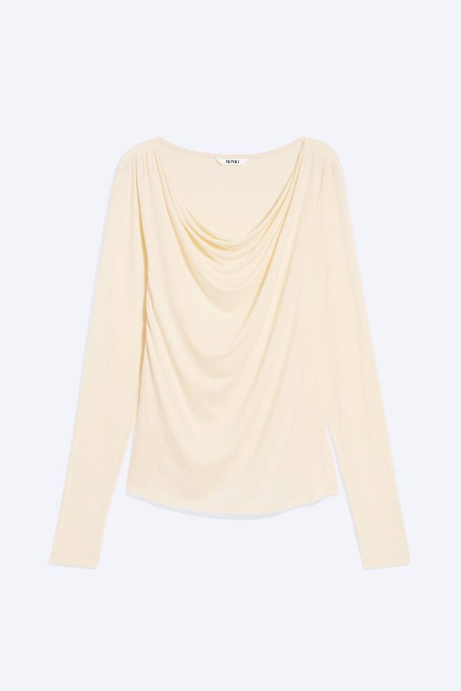A light cream-coloured long-sleeve top is shown from the front, featuring a draped cowl neckline with soft folds cascading down the centre. The garment features long, slim-fitting sleeves and a straight hemline. - 1