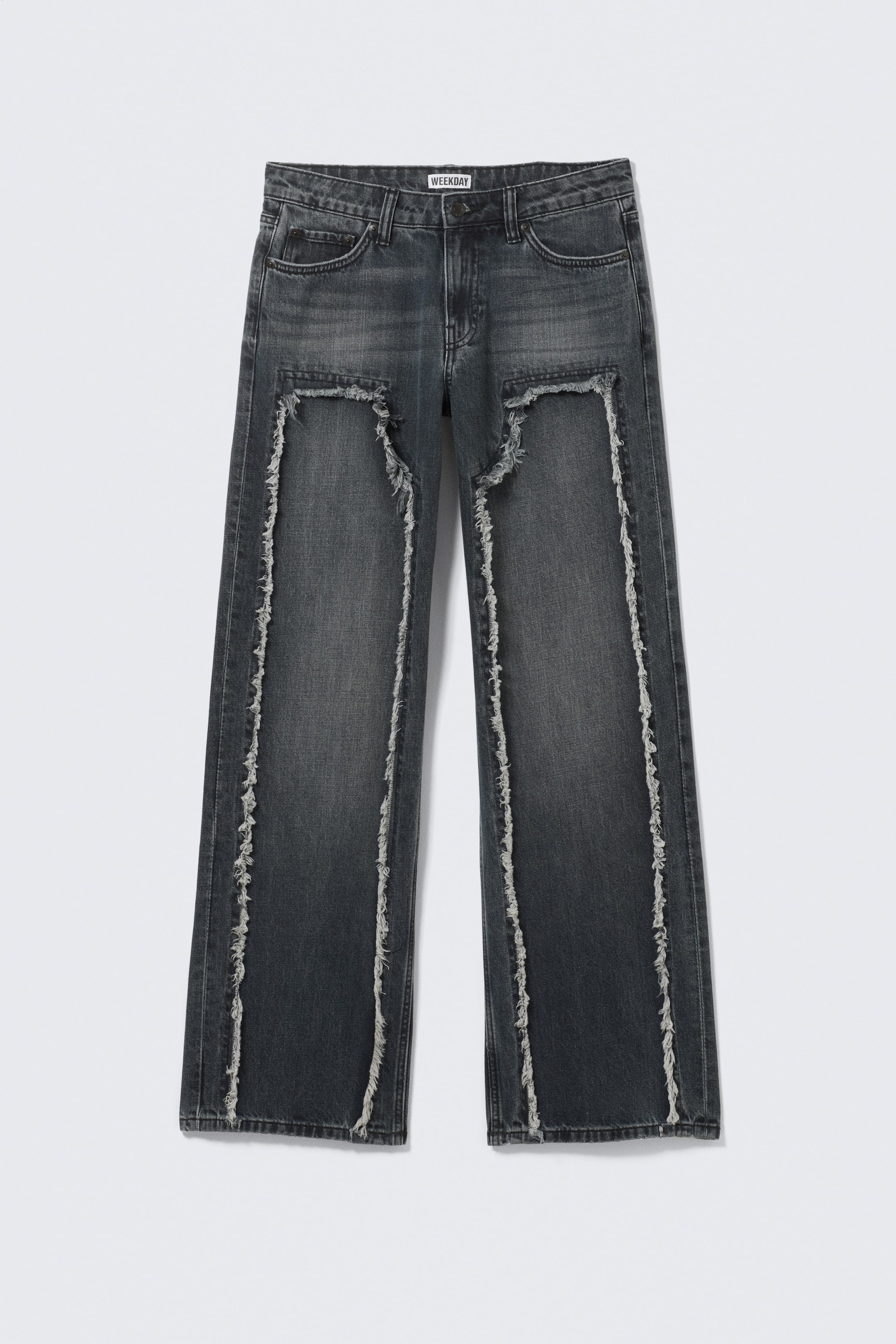 Agrandir l'image: Un jean en denim délavé gris foncé est présenté de FACE, avec de grandes découpes irrégulières sur le haut des cuisses, bordées de franges blanches proéminentes. Des lignes verticales de denim brut et effiloché descendent également le long de chaque jambe, créant une apparence déconstruite.