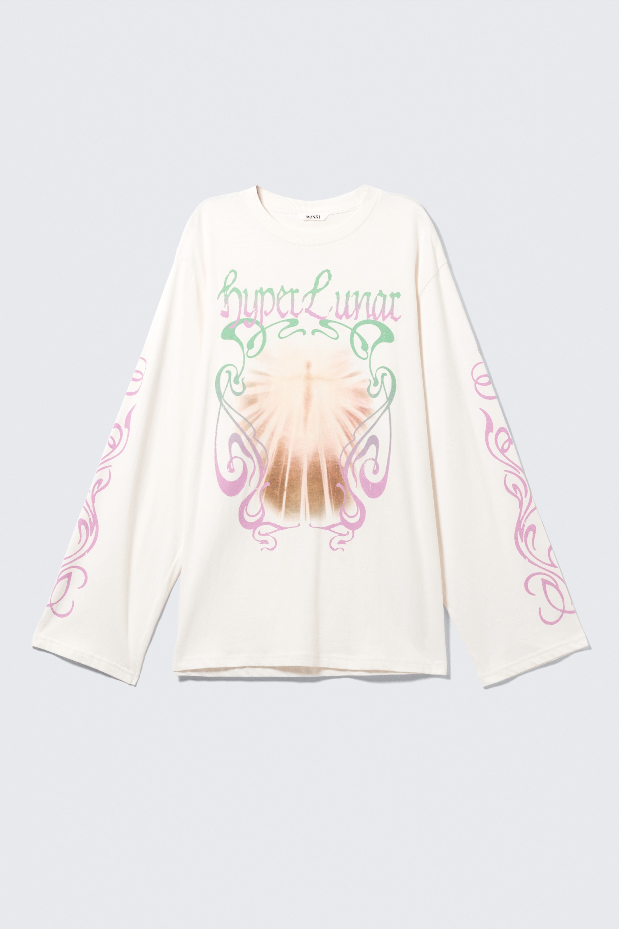 View larger image: A cream long-sleeved t-shirt is presented from the FRONT, featuring a crew neck and an oversized fit. Its central graphic is depicting "hyper Lunar" text in green and purple above a radiating sun-like design framed by swirling Art Nouveau-style lines in green and purple, with matching purple swirling patterns extending down the outer sides of both sleeves.