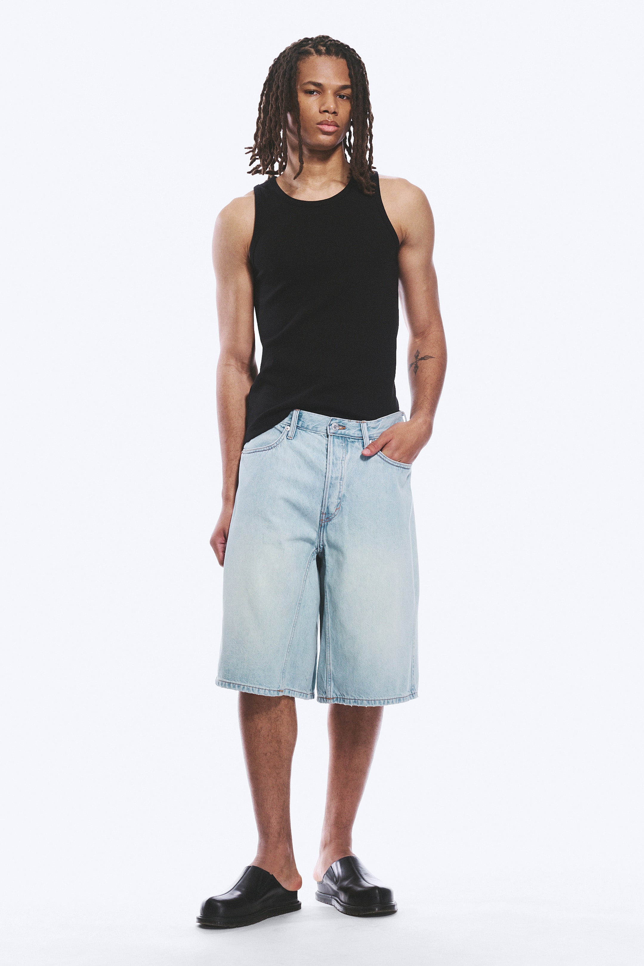 Zobacz większy obraz: Szorty z jasnego denimu skierowane są do przodu, charakteryzują się luźnym, swobodnym krojem, który sięga tuż nad kolano. Zaprojektowane z wysokim stanem, widocznymi szlufkami na pasek, guzikiem, zamkiem błyskawicznym i dwoma przednimi kieszeniami.