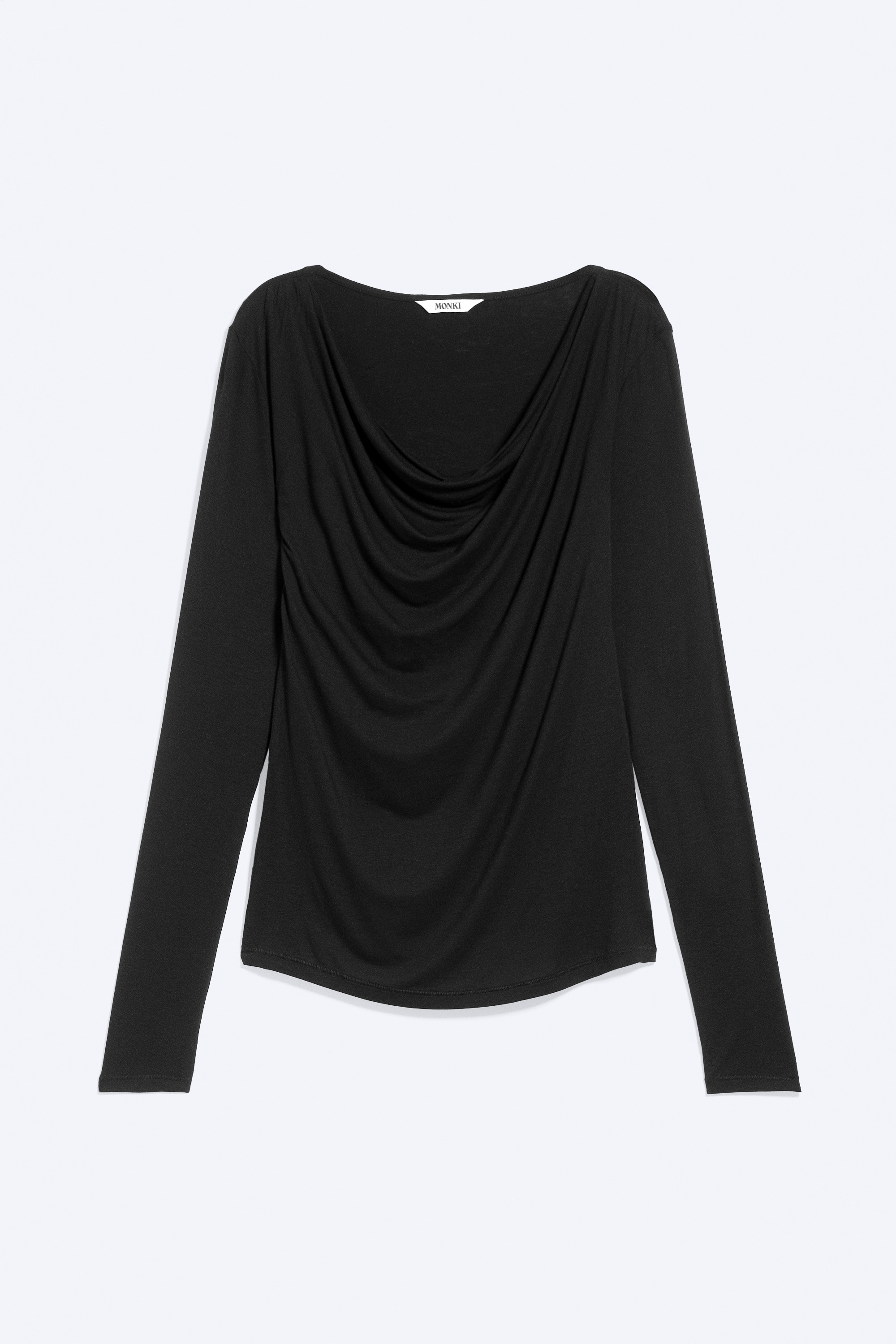 La modella indossa un top nero slim fit a maniche lunghe, caratterizzato da uno scollo a cowl drappeggiato e asimmetrico e da dettagli arricciati in vita. Il top è abbinato a jeans in denim blu.