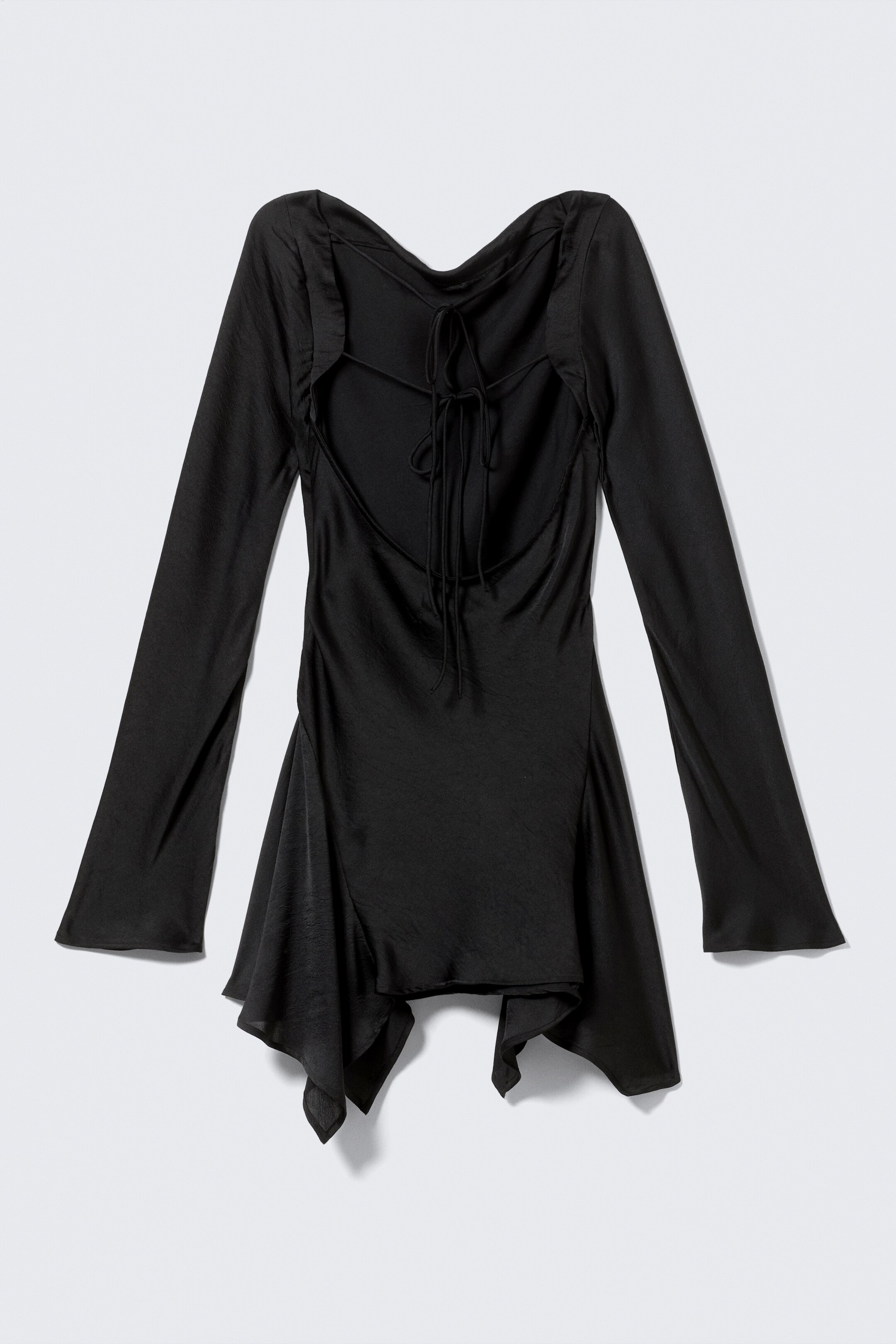 View larger image: A black satin-like top is being presented from the back, featuring a deep, draped open back with thin, crisscrossing ties, long, subtly flared sleeves, and an asymmetrical, pointed hemline.