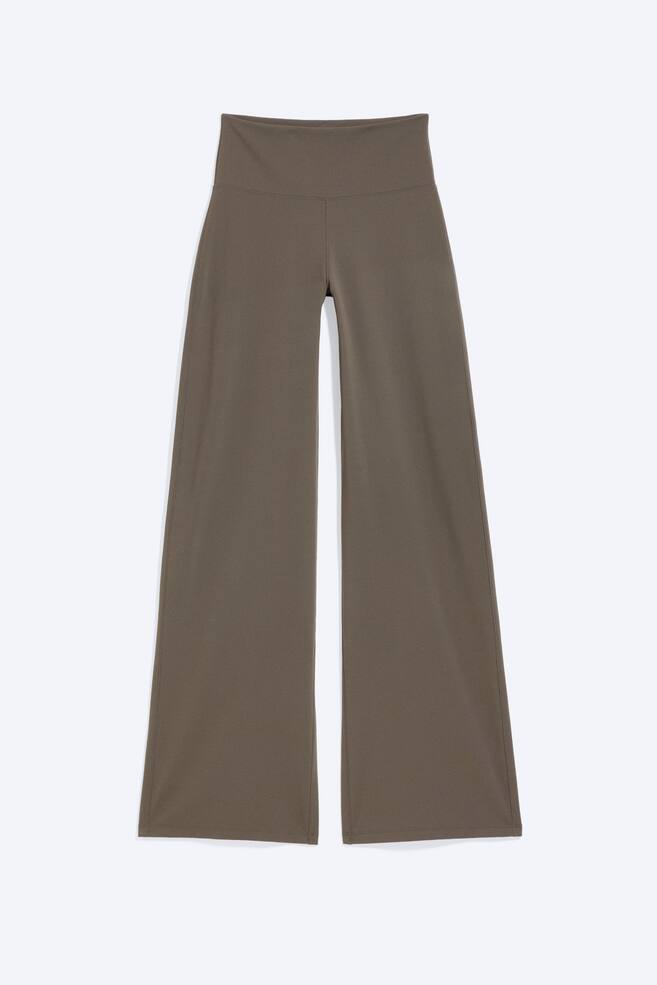 Le pantalon vert olive foncé présente une taille haute, une large ceinture et une coupe longue à jambes larges avec une finition en tissu lisse. - 1