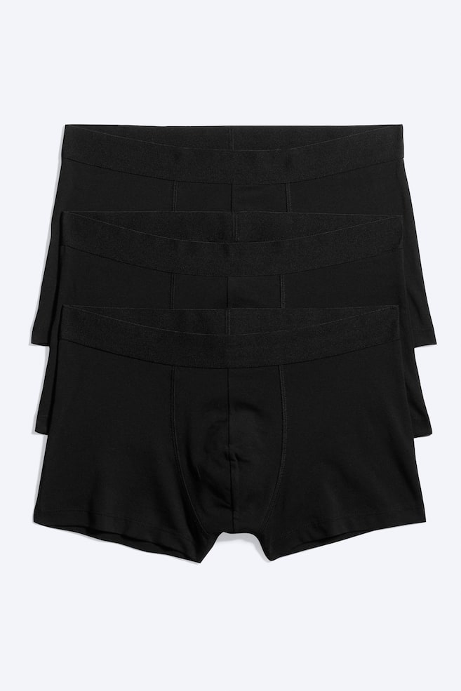 Tre par ensfarvede sorte boxer briefs er vist i en lodret stablet, frontvendt opstilling. Hvert par har en bred elastisk linning, en formsyet frontpung med lodrette sÃ¸mme og korte ben. - 1