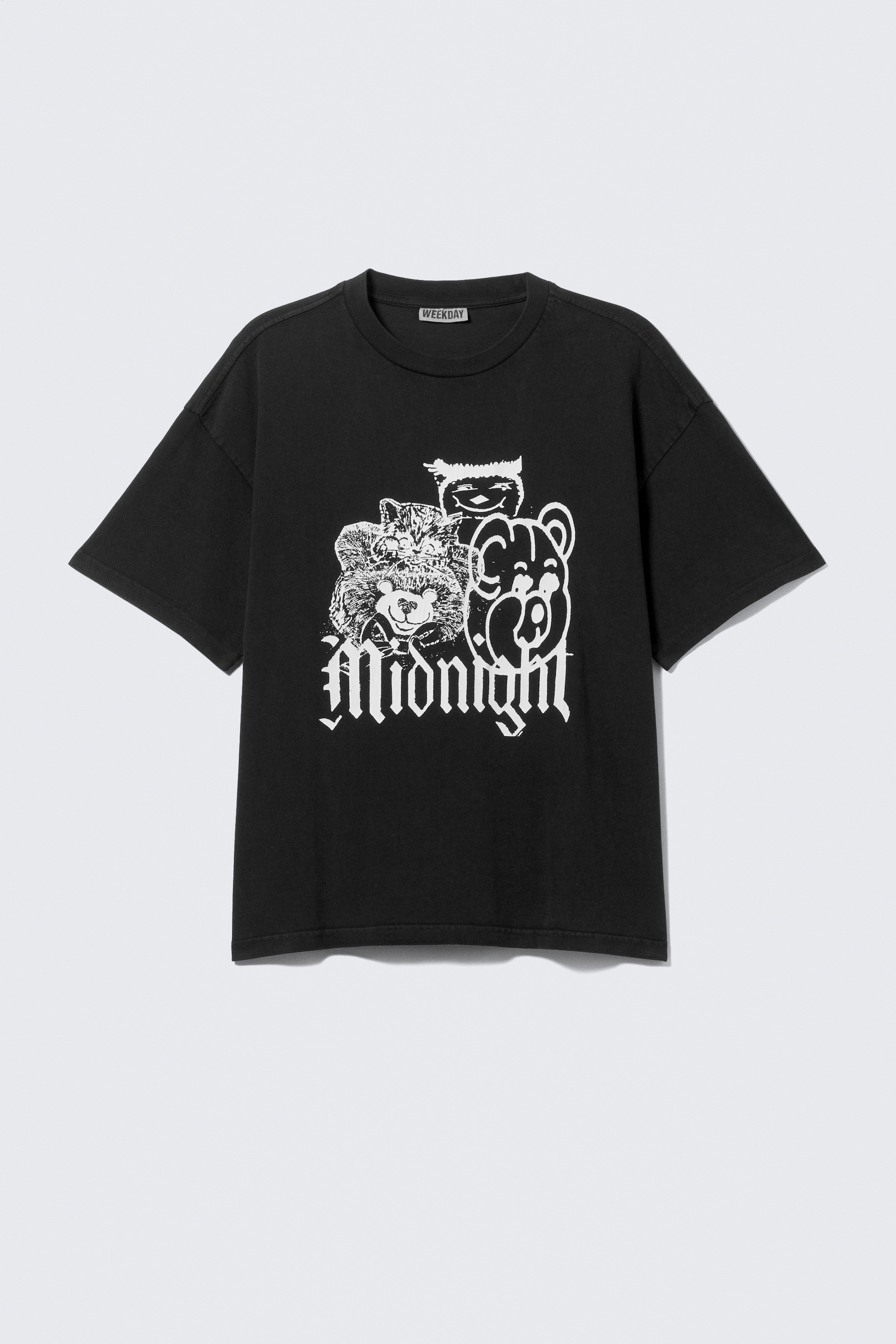 View larger image: A black, loose-fitted t-shirt is shown from the FRONT, featuring a boxy silhouette, a ribbed crew neck, dropped shoulders, and twin-stitched hemlines at the sleeves and bottom. A white graphic print is displayed on the chest, depicting stylized animal faces and the word "Midnight" in gothic script, with a "WEEKDAY" brand tag visible at the inner back neck.