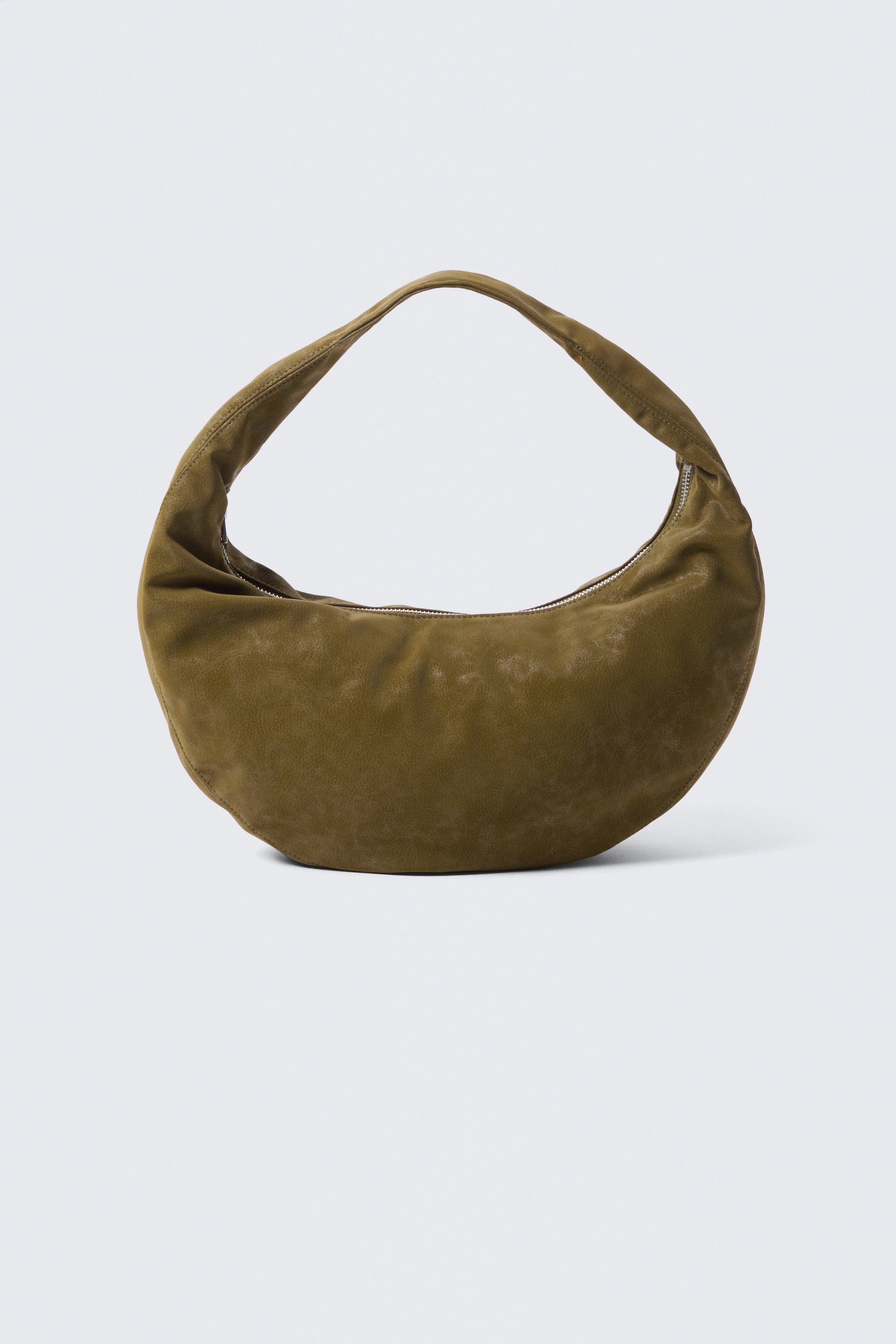 Agrandir l'image: Le sac à main en forme de croissant est orienté vers l'avant, confectionné en daim vert olive patiné. Il est doté d'une large bandoulière intégrée et d'une fermeture éclair argentée le long de son bord supérieur incurvé.