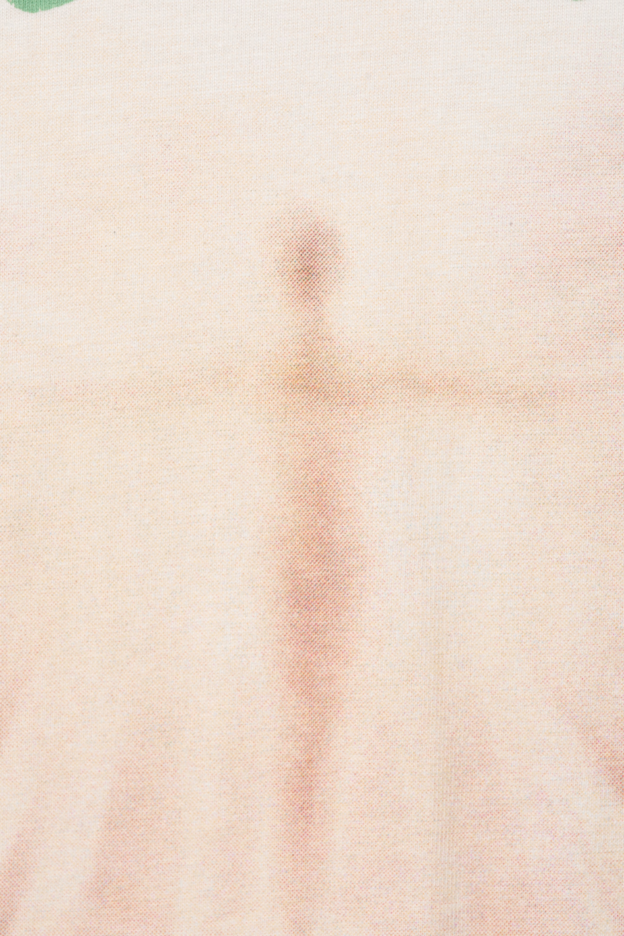 View larger image: A light cream-colored fabric is featuring a faint, translucent reddish-brown image of a human figure with outstretched arms. The fabric is displaying a fine, visible texture, and a small green detail is visible in the top left corner.