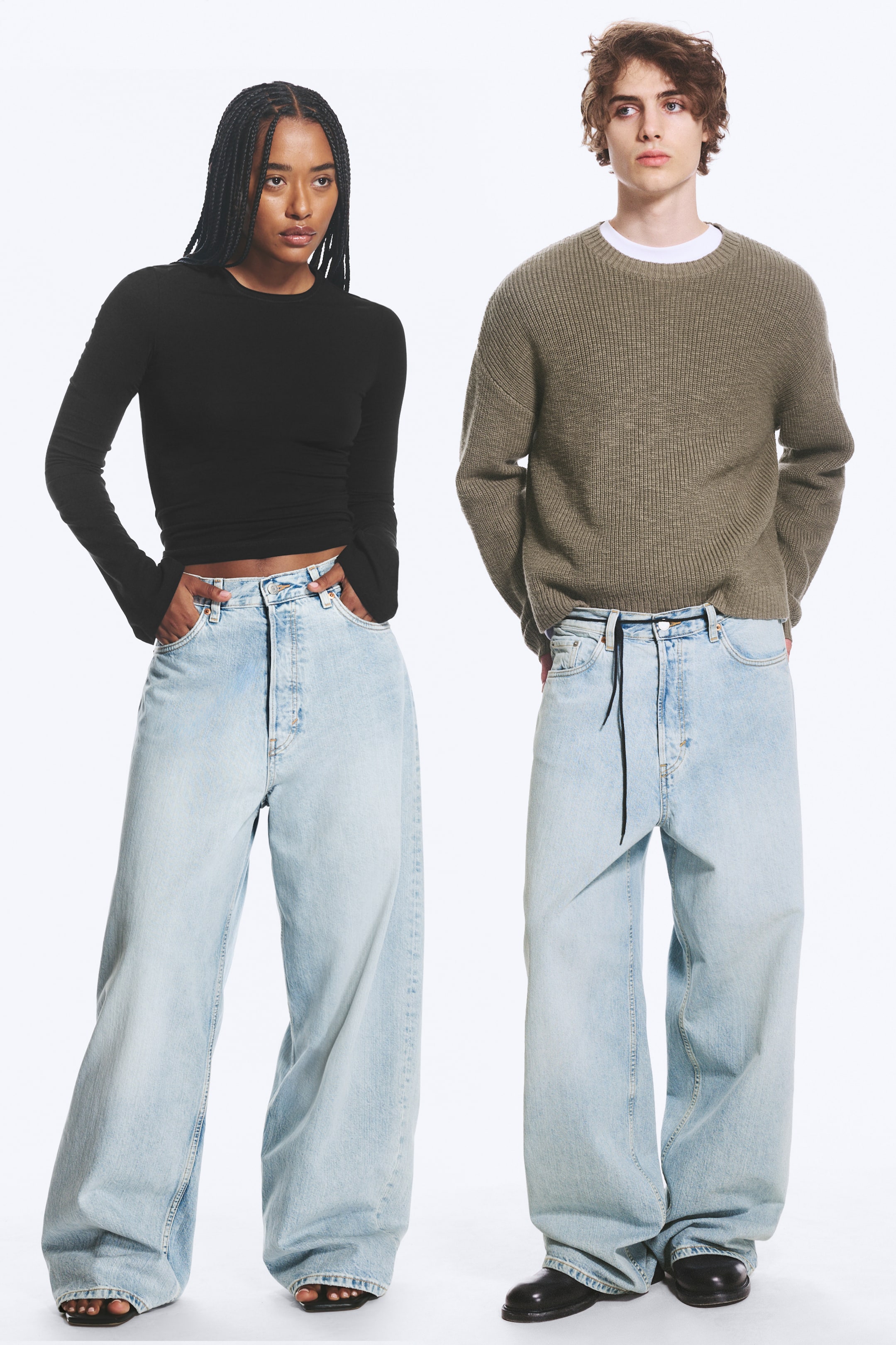 Agrandir l'image: Une paire de jeans unisexes bleu clair taille mi-haute est présentée de face, avec une coupe ample et une jambe baggy. Les jeans affichent un design classique à cinq poches, de grandes poches arrière et une braguette à boutons apparente.