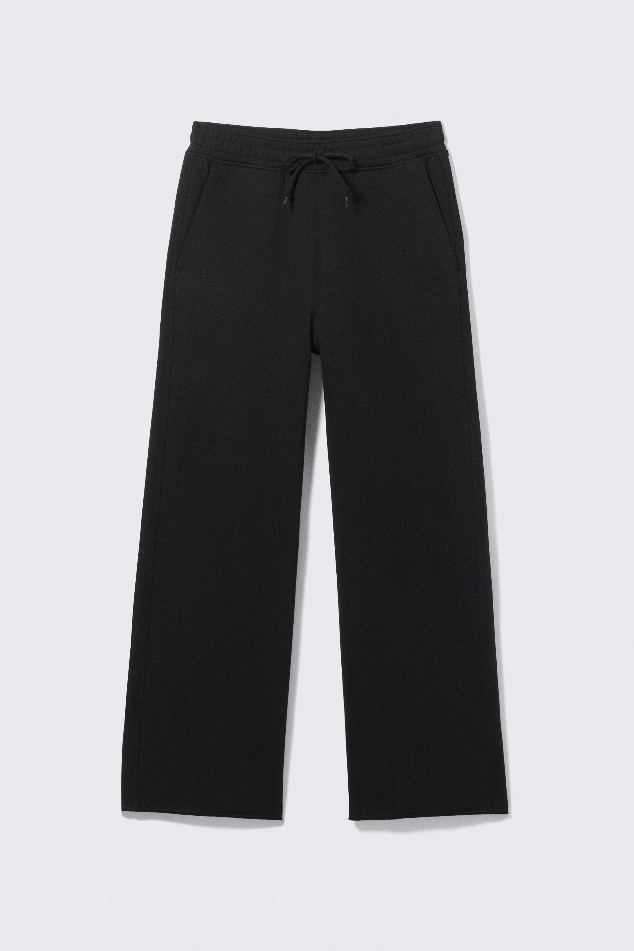 Agrandir l'image: Un pantalon de survêtement noir à jambes larges est présenté de FACE, avec une large ceinture à cordon de serrage nouée et des poches latérales inclinées. Les ourlets semblent non traités.