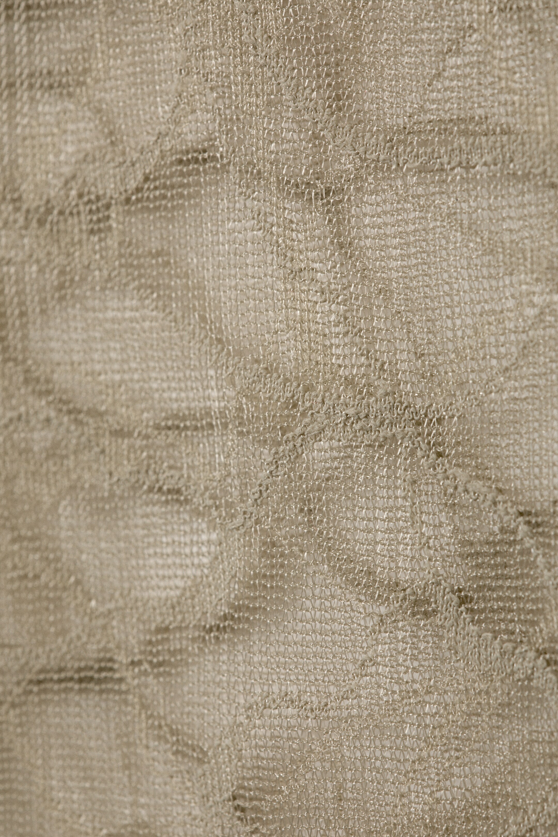 Agrandir l'image: Un matériau en tissu beige clair présente une structure à mailles fines et ouvertes. Le tissu affiche des plis irréguliers et des ondulations subtiles sur sa surface texturée.