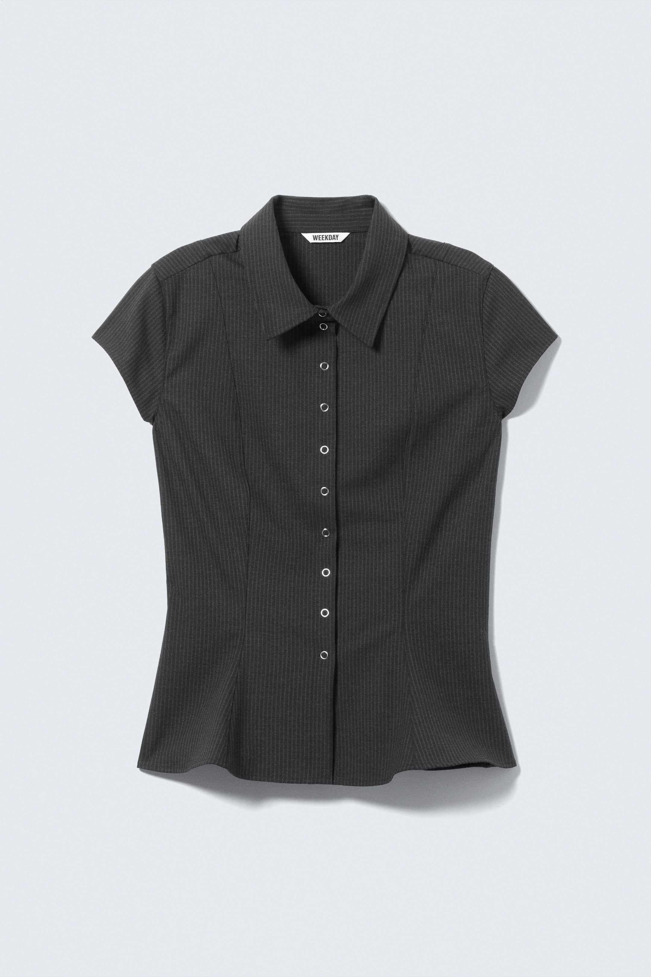 Agrandir l'image: Une chemise à manches courtes, ajustée et de couleur gris foncé, est présentée de FACE. Elle se distingue par un col pointu, des manches courtes et une patte centrale avec des boutons-pression de couleur argentée. Le tissu présente de subtils rayures verticales, et l'ourlet est à bord franc.