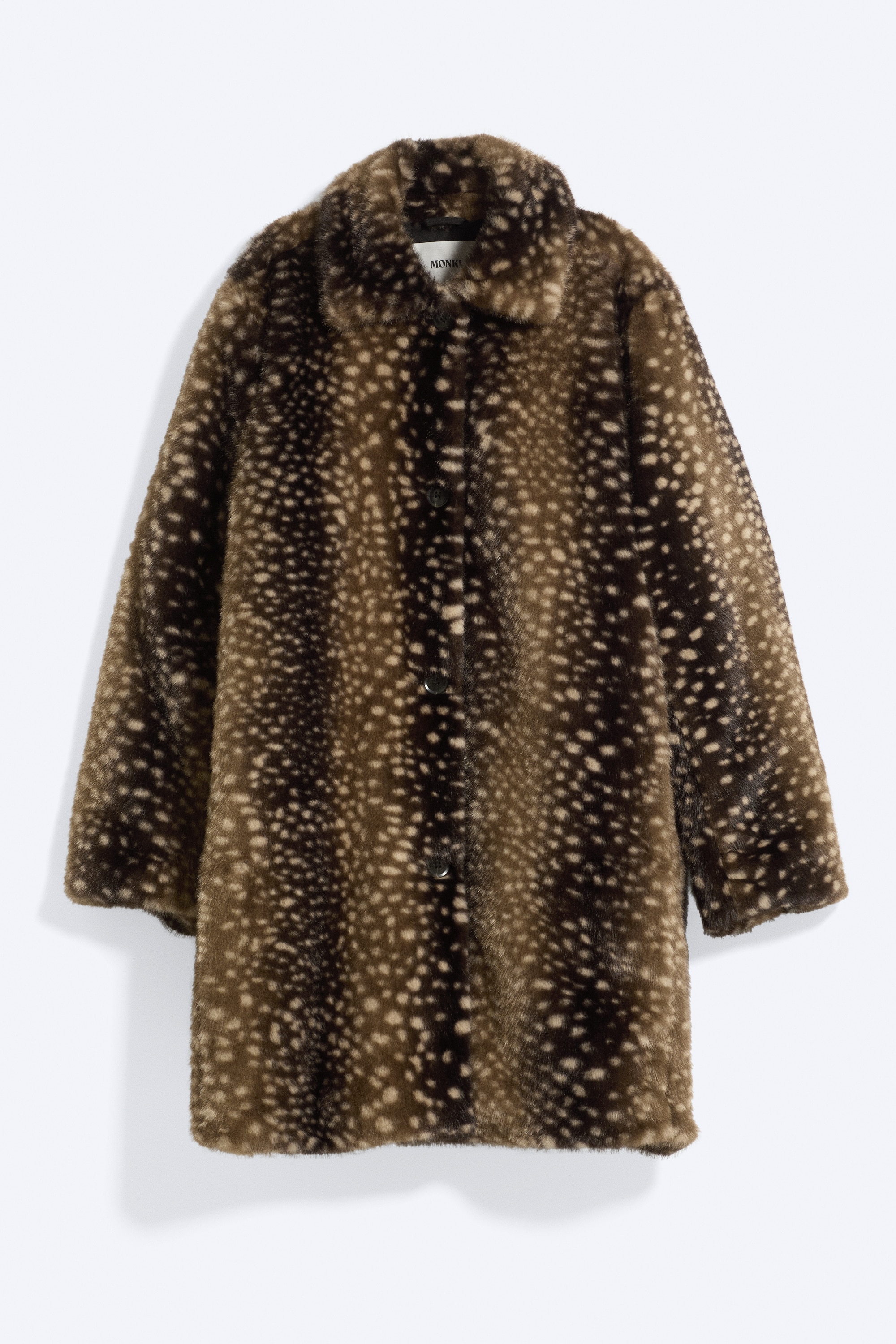 Een imitatiebont car coat met een bruin en beige gespikkeld patroon wordt gedragen door het model. De jas heeft een klassieke kraag en een knoopsluiting met Ã©Ã©n rij knopen, en wordt gecombineerd met een crÃ¨mekleurig overhemd met knoopsluiting en een zwarte pantalon.