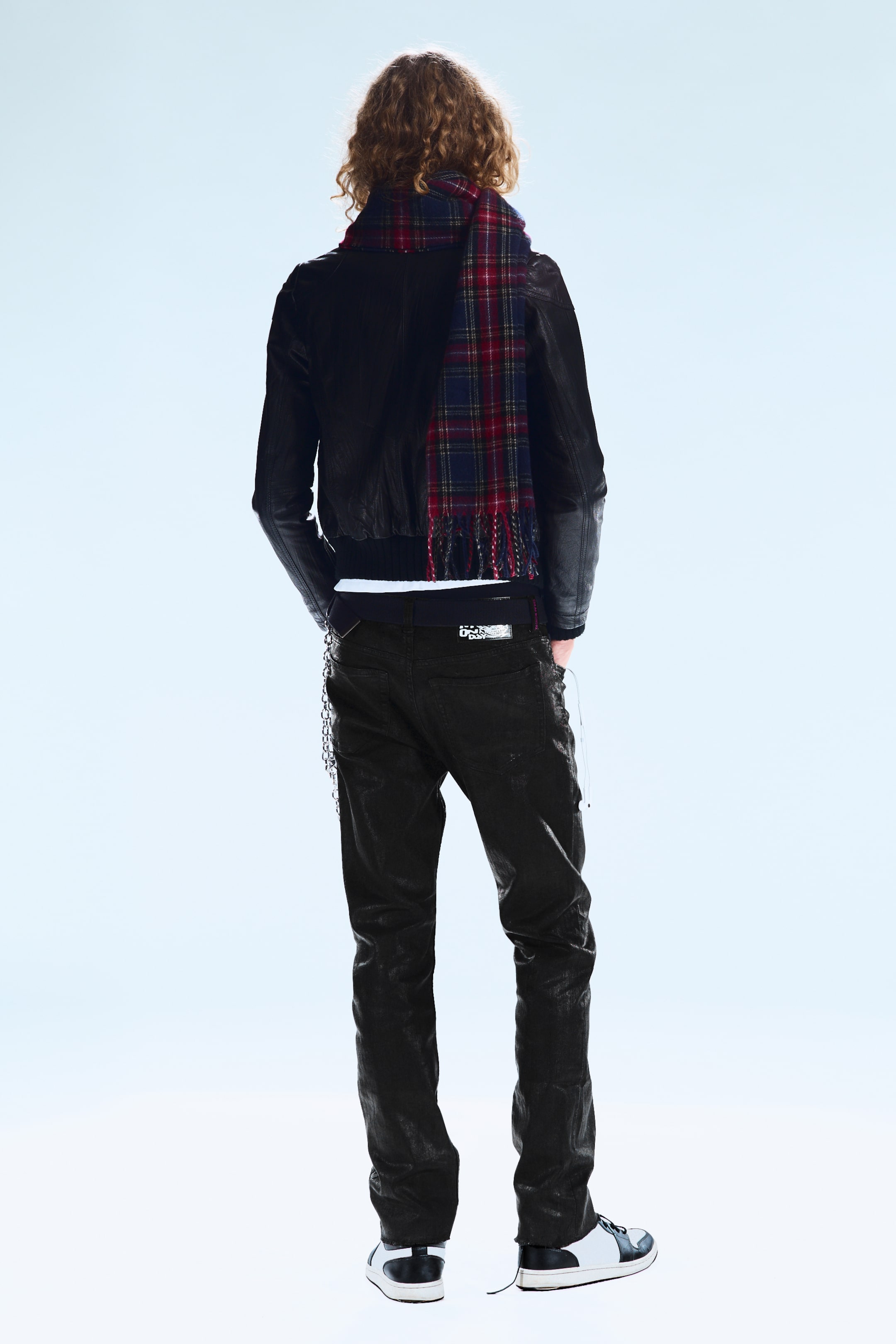Visualizza immagine più grande: Jeans neri skinny fit, caratterizzati da una texture visibilmente screpolata, sono indossati da un modello che sta in piedi con la schiena rivolta verso l'osservatore. Una catena di metallo è attaccata a un passante della cintura sui jeans.