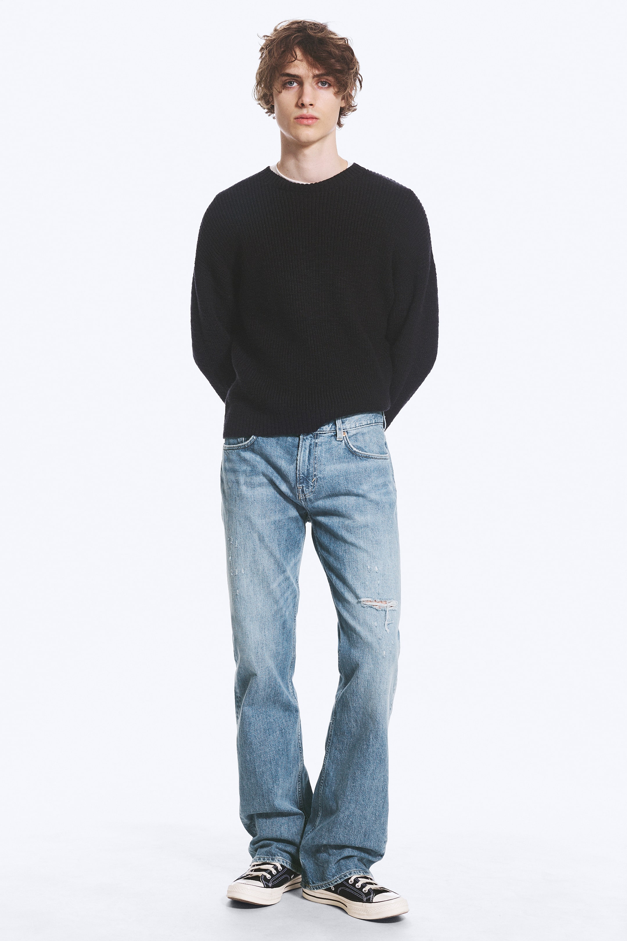 Visualizza immagine più grande: I jeans azzurri presentano un lavaggio effetto usato con uno strappo visibile sul ginocchio destro. Sono progettati con una vestibilità dritta, dotati di tasche frontali e passanti per cintura visibili da un'angolazione frontale.
