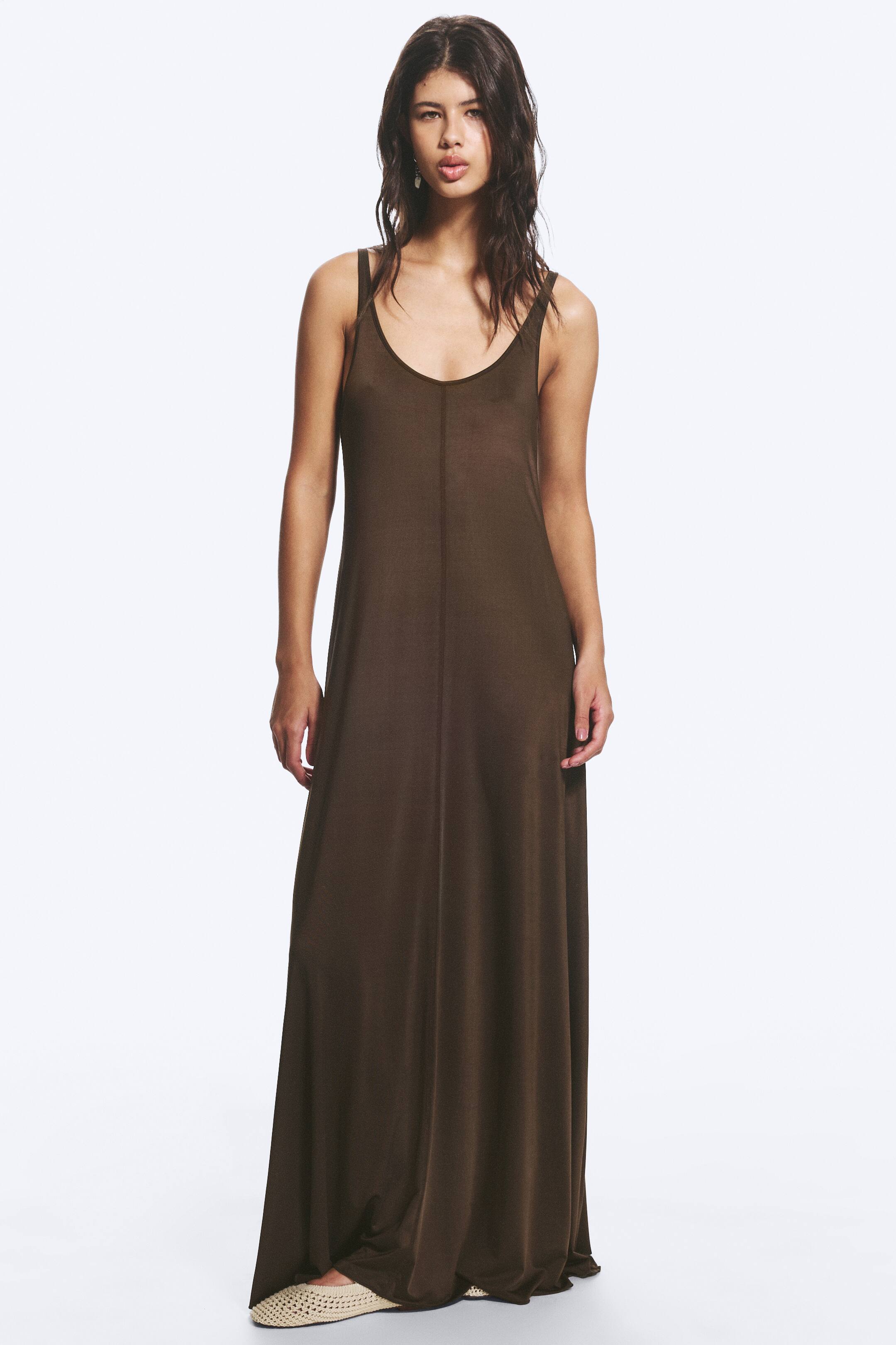 View larger image: A brown sleeveless maxi dress featuring a scoop neckline and thin shoulder straps. It presents a relaxed, flowy fit with a visible centre seam down the front.