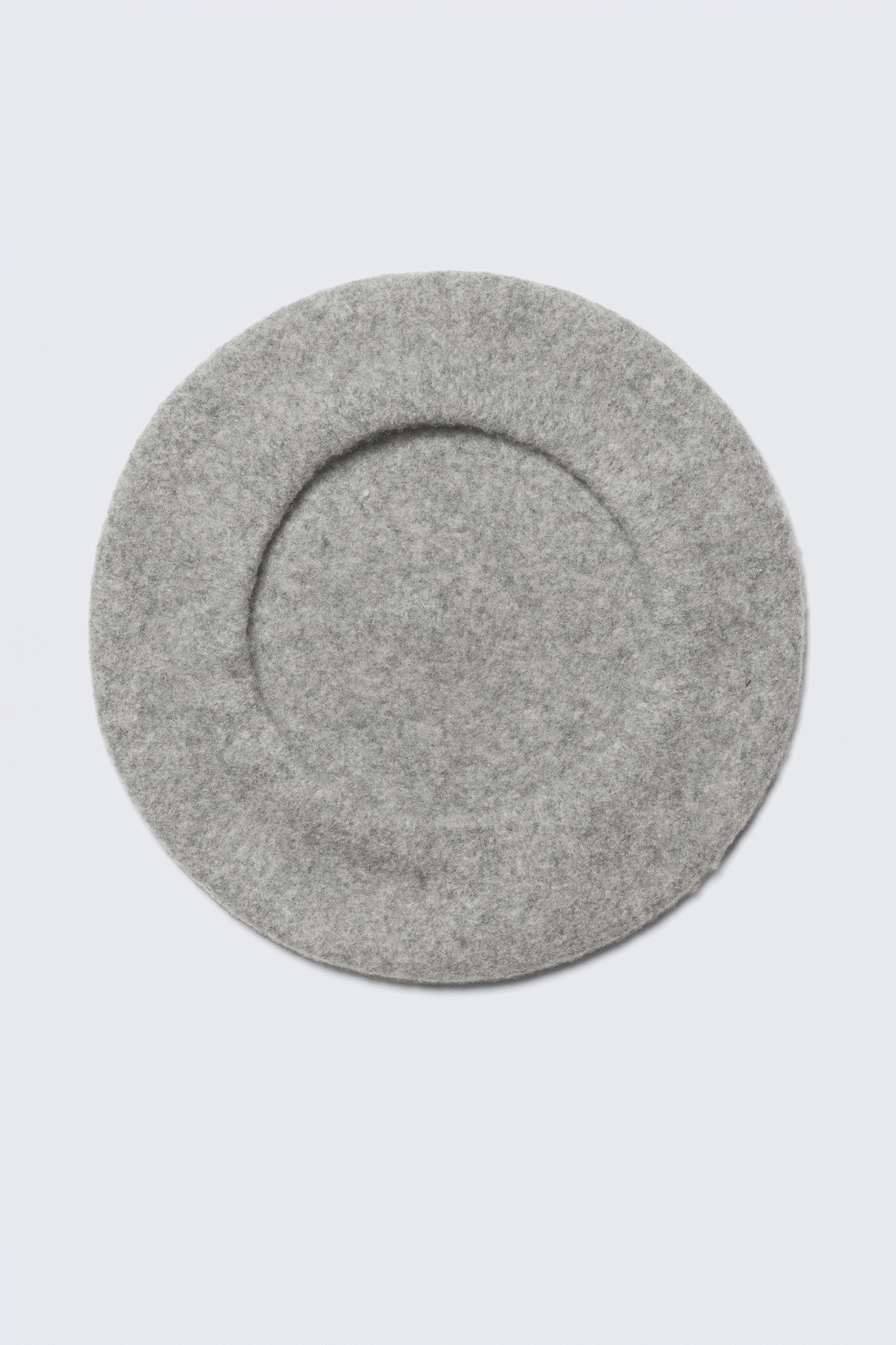 Agrandir l'image: Un béret en feutre gris présente une forme circulaire vue de dessus, avec un bandeau circulaire subtilement défini.