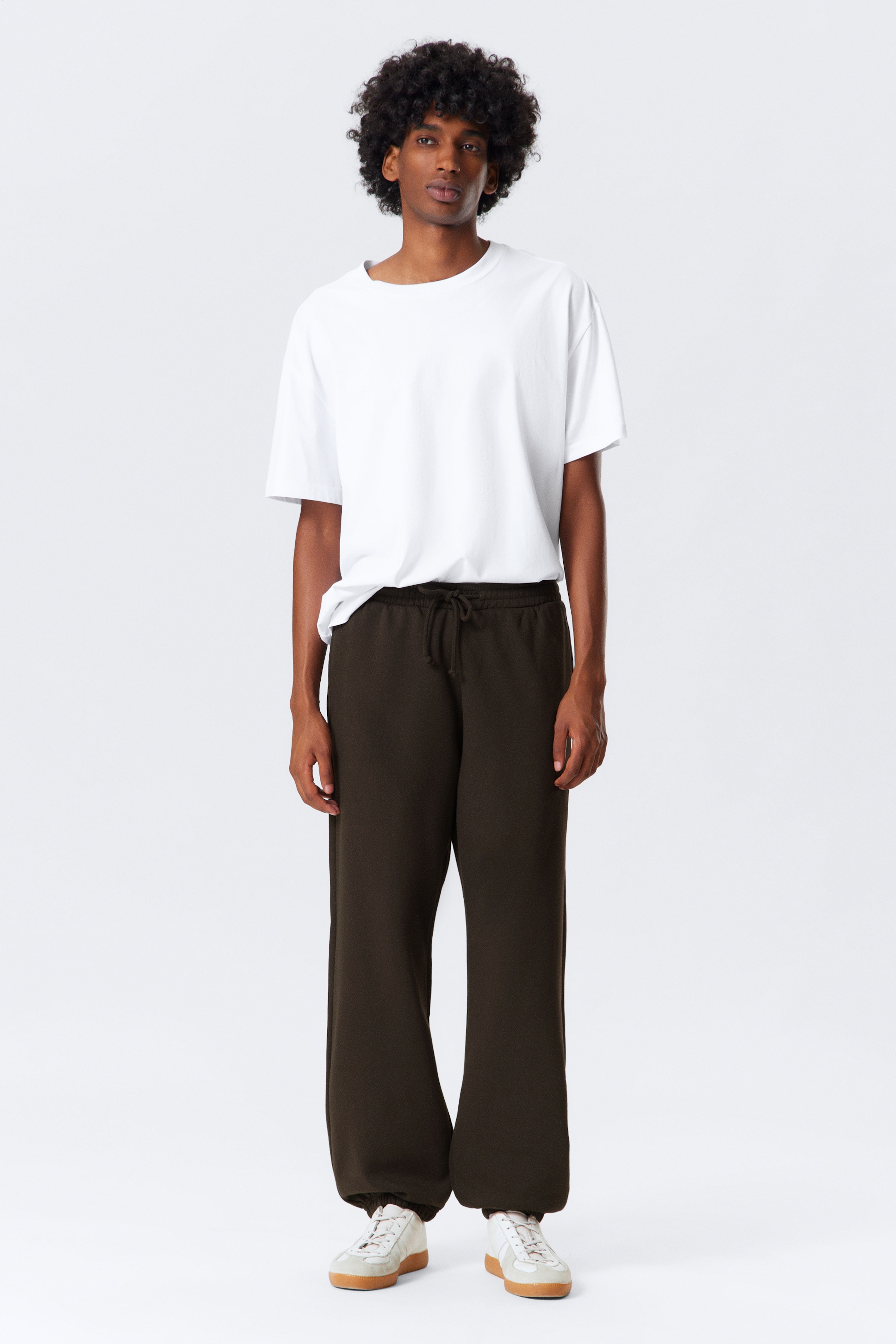 Visualizza immagine più grande: Pantaloni della tuta marrone scuro presentano una vestibilità rilassata e a gamba larga con una vita elasticizzata con coulisse. I polsini elasticizzati si raccolgono alle caviglie, creando un leggero effetto slouch.