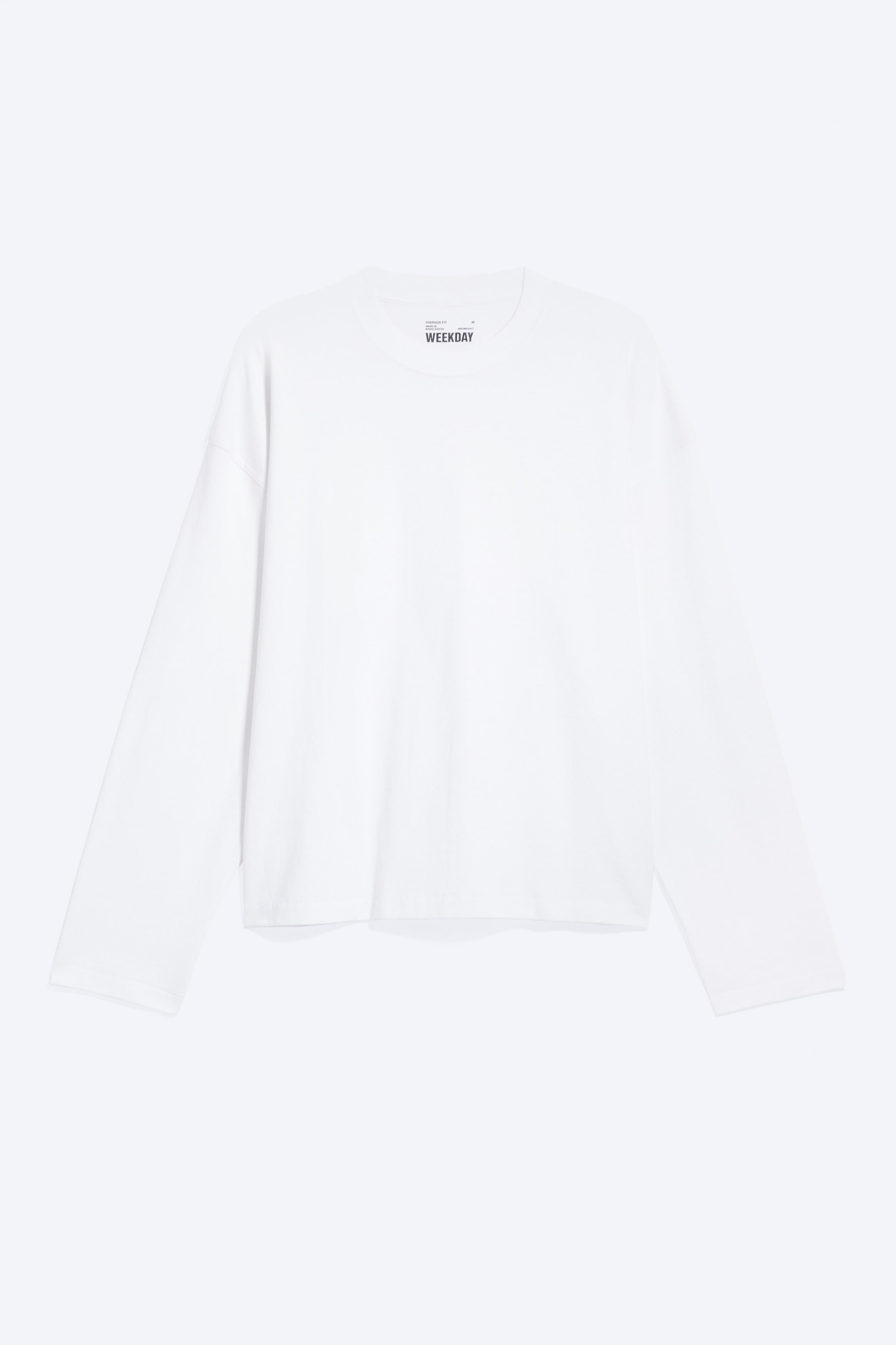 Agrandir l'image: Le haut ample à manches longues est présenté de face, dans une couleur blanche unie, avec un col rond, des épaules tombantes et des manches larges et décontractées. Une petite étiquette de marque noire est visible près de l’encolure.