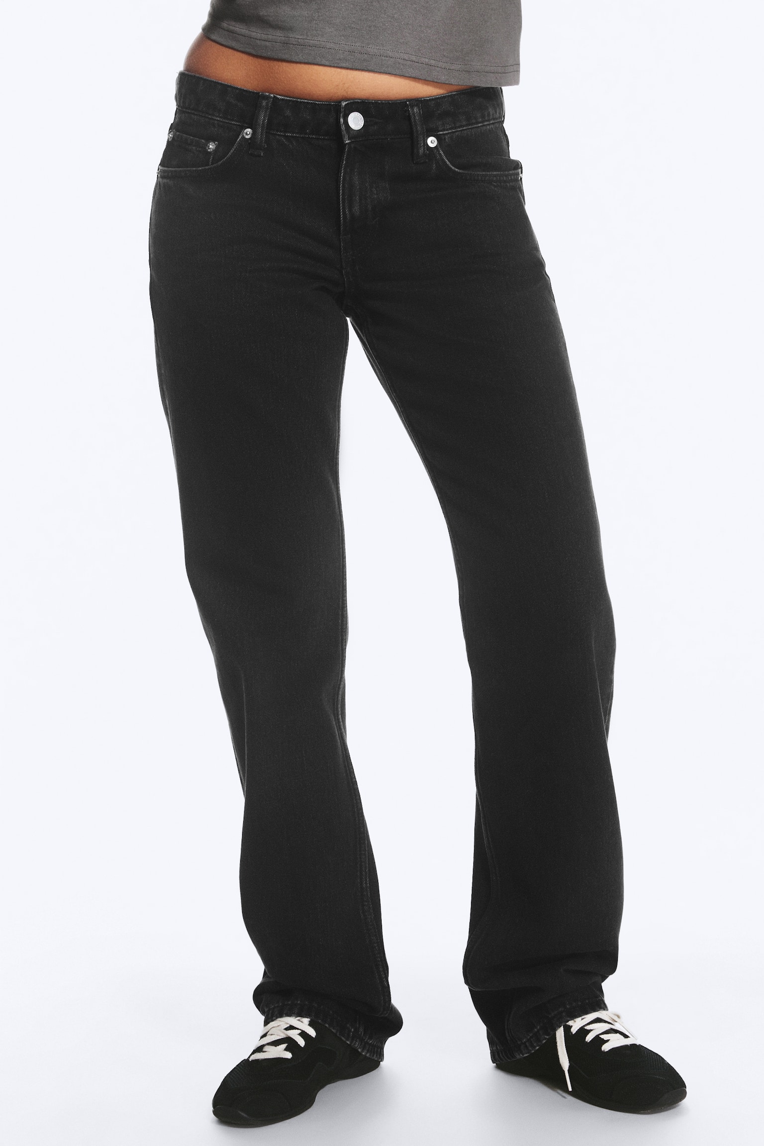 Un jean droit gris foncé est présenté de face, mettant en valeur une taille basse et un design classique à cinq poches avec des rivets ton cuivré et une fermeture à bouton ton argenté. Le jean affiche une coupe regular avec une texture denim légèrement délavée et de longues jambes droites. - 1