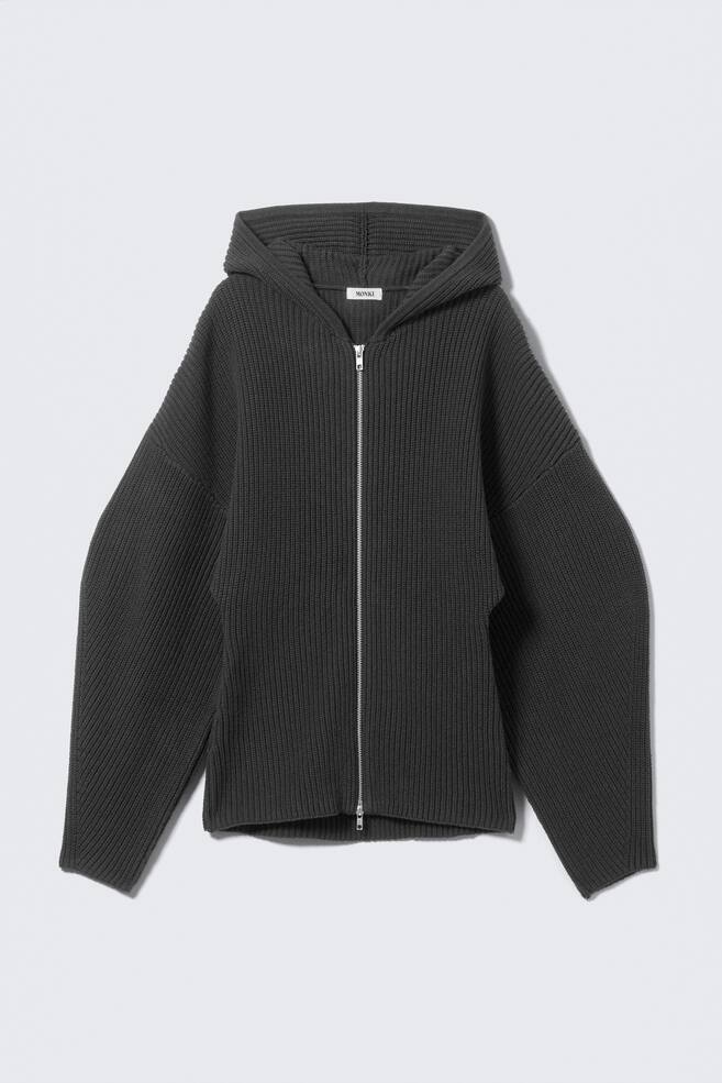 A charcoal grey knitted zip-up hoodie is being displayed front-facing. It is featuring a full-length silver-tone zipper, and it is showcasing an integrated hood, wide, relaxed sleeves, and a consistent vertical ribbed knit texture throughout. - 1
