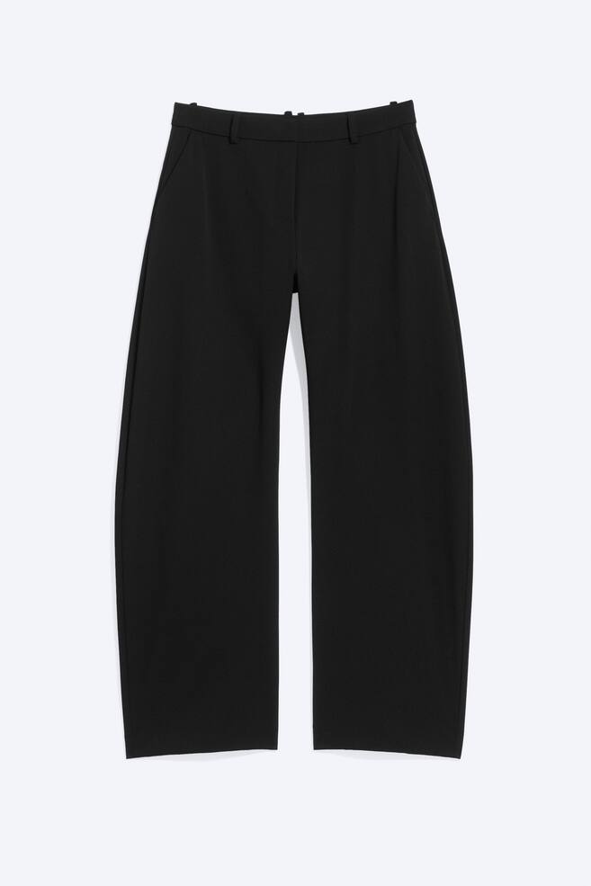 Schwarze, weit geschnittene Hosen präsentieren sich flach von vorne. Sie zeichnen sich durch eine glatte Textur, einen Bund mit Gürtelschlaufen und seitliche Eingrifftaschen aus. - 1