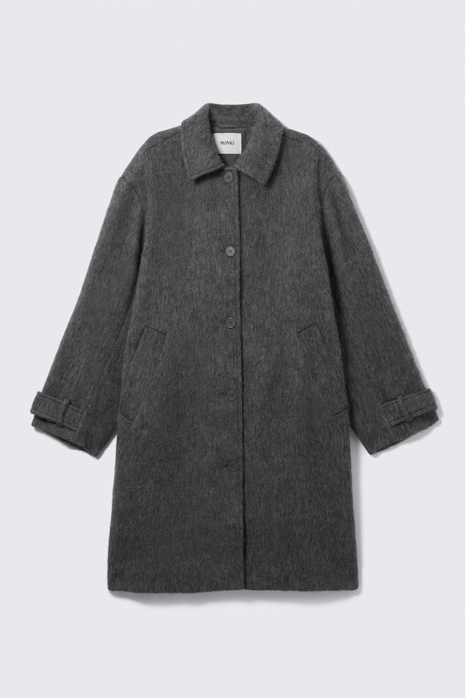 A dark gray coat with a brushed texture is seen from the FRONT, featuring a classic point collar, a four-button front closure, two angled welt pockets, and long sleeves with adjustable strap details on the cuffs. - 1