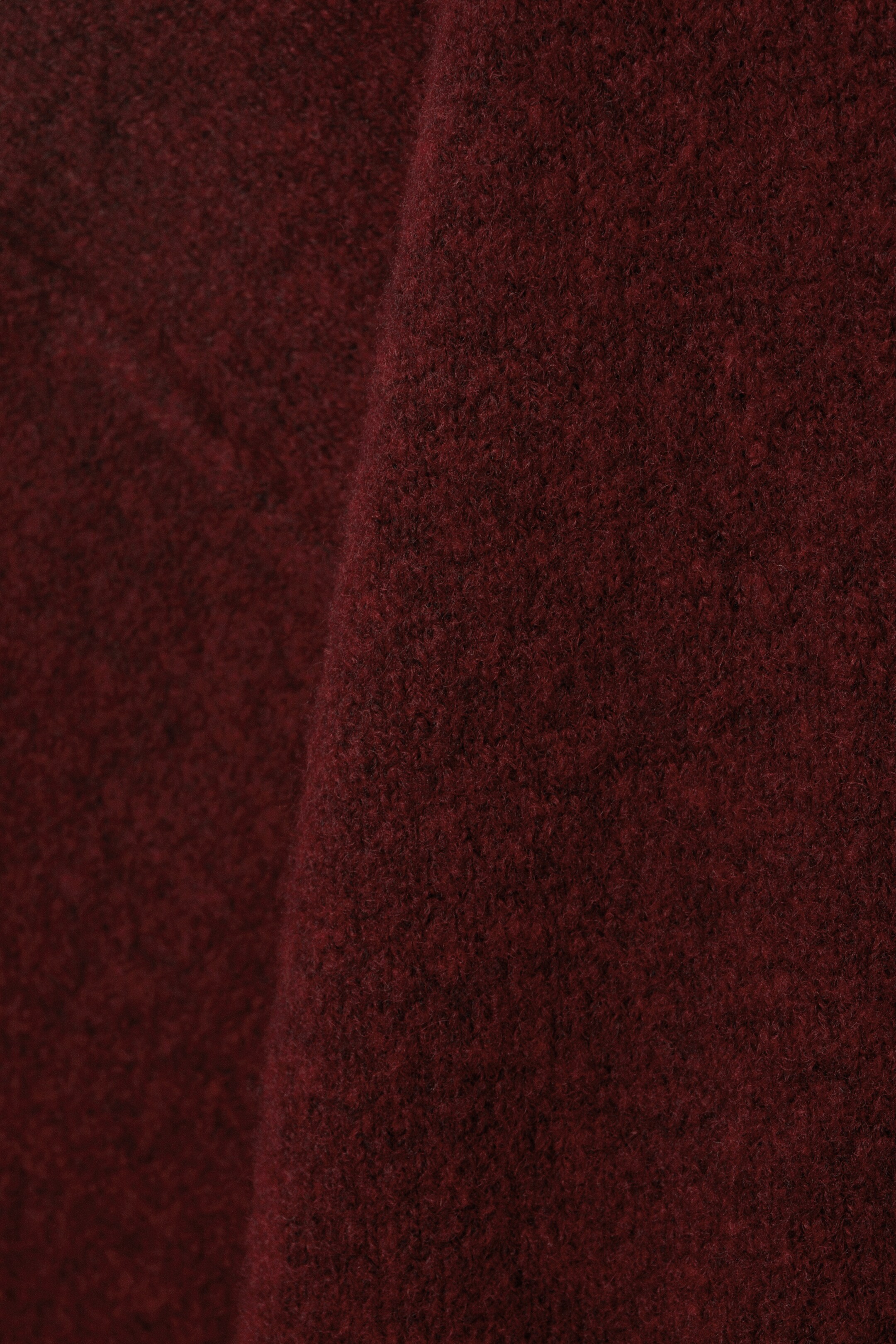 Größeres Bild ansehen: Ein tiefroter Strickpullover präsentiert seine weiche, leicht flauschige Stoffstruktur.