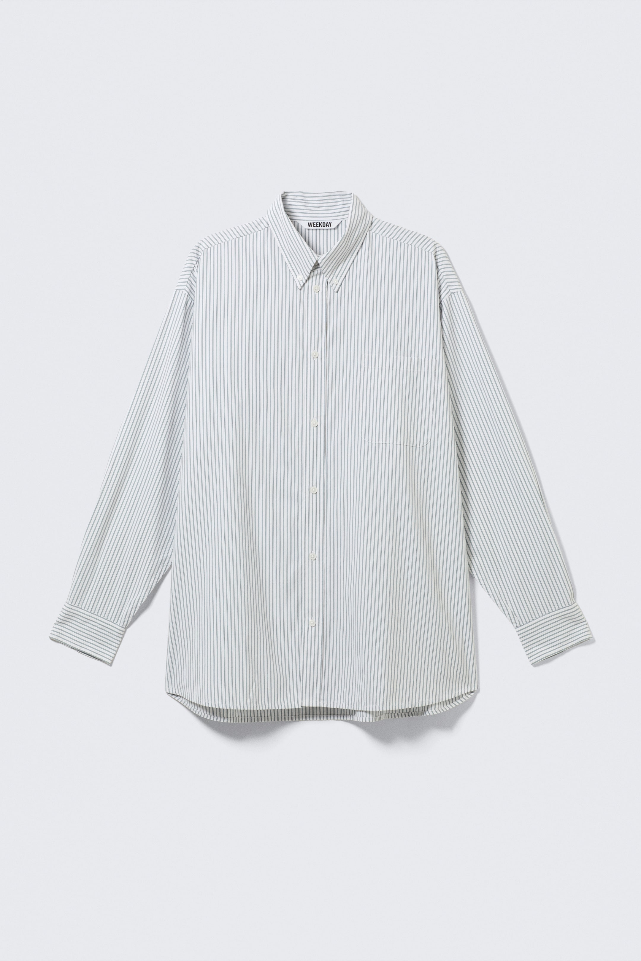 View larger image: A long-sleeve shirt is presented from the FRONT, featuring thin grey vertical stripes on a white background. It is designed with a button-down collar, a full button placket with white buttons, a single patch pocket on the left chest, long sleeves with buttoned cuffs, and a curved hem.