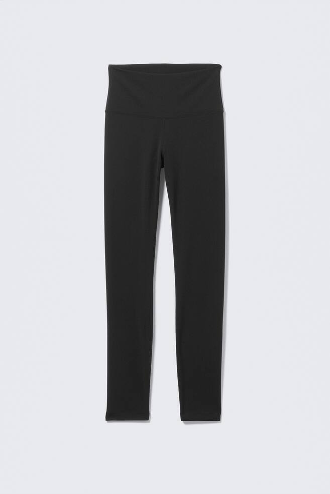 Schwarze Leggings werden von vorne präsentiert, mit einem hoch taillierten Design und einem breiten, glatten Bund. Der glatte Stoff bildet eine eng anliegende, gerade Silhouette. - 1