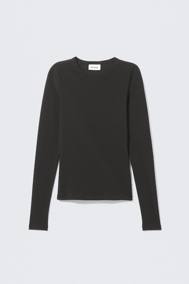 En mörkgrå långärmad topp presenteras FRAM, med en smal passform, en rund hals och raka fållar. En vit rektangulär etikett med texten "WEEKDAY" är synlig inuti den bakre halsringningen. - 1