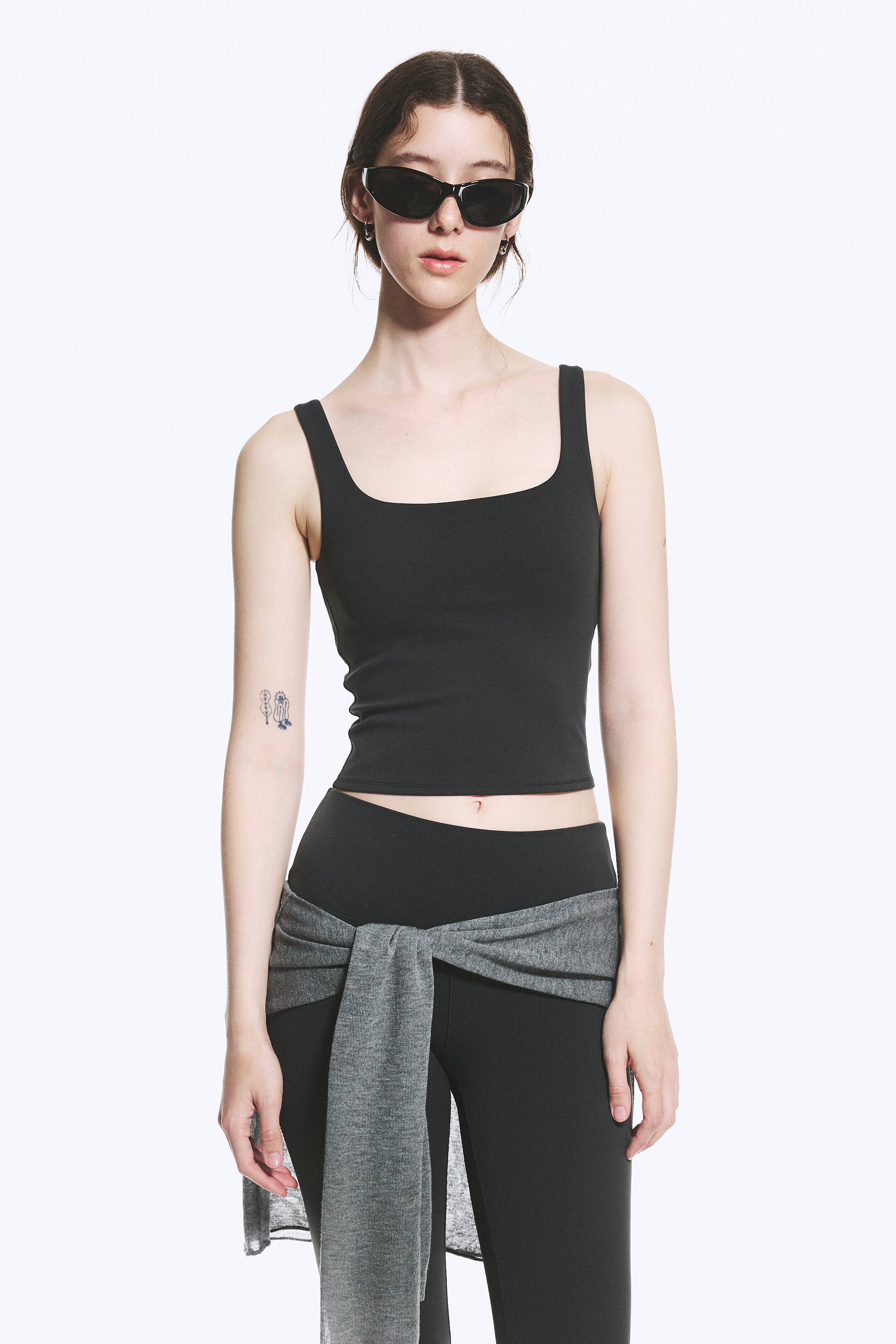 Visualizza immagine più grande: Un top nero è presentato, rivolto in avanti. Presenta uno scollo quadrato e spalline larghe, mostrando anche un design aderente e corto che termina sopra l'ombelico.