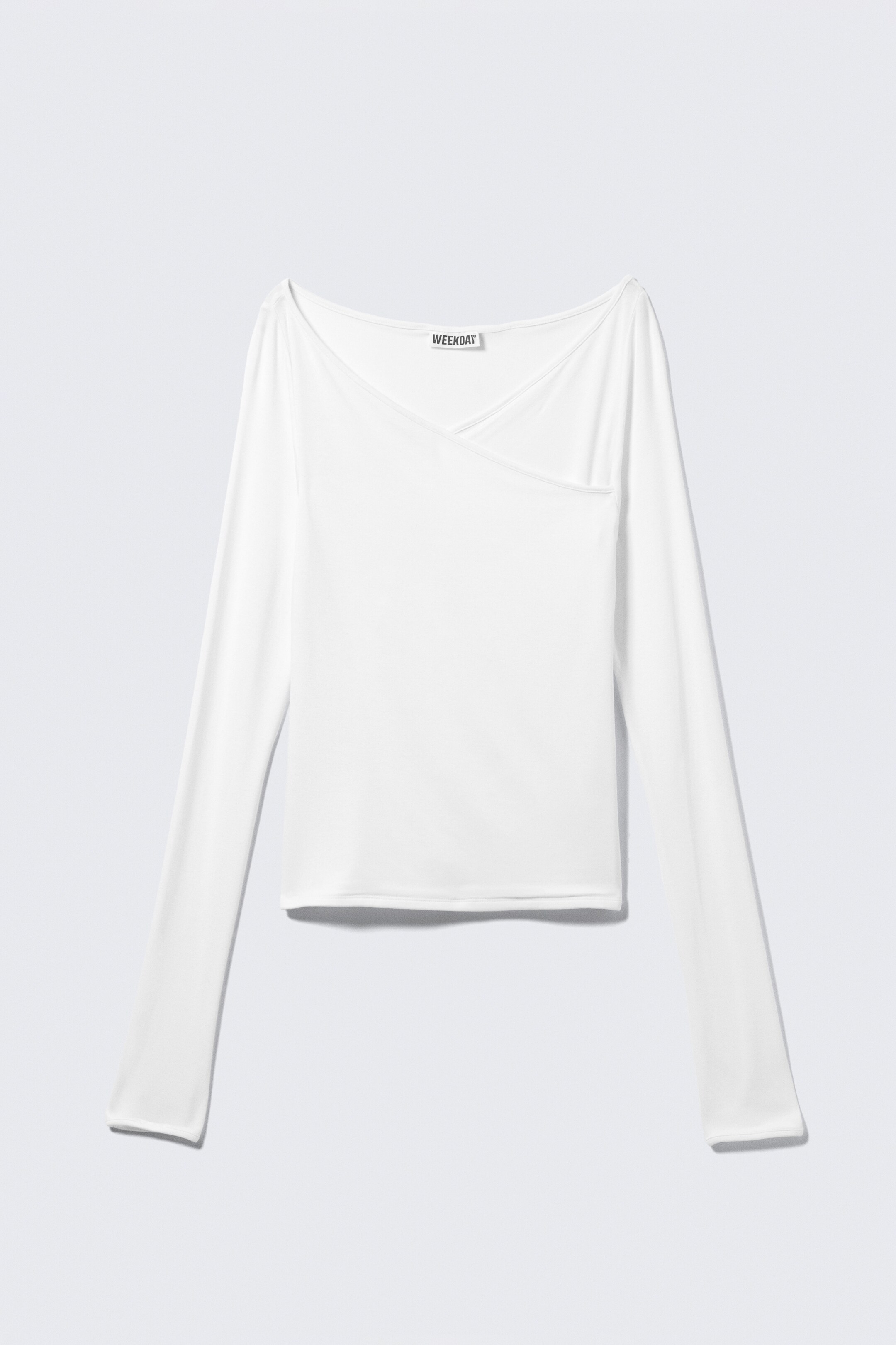 Grösseres Bild ansehen: Das weisse langärmelige Oberteil wird von vorne präsentiert und zeigt eine schlanke Silhouette. Es ist mit einem asymmetrischen Wrap-Ausschnitt gestaltet, der einen drapierten Effekt erzeugt, und wird mit sauberer Einfassung entlang der Manschetten und des Ausschnitts abgeschlossen.