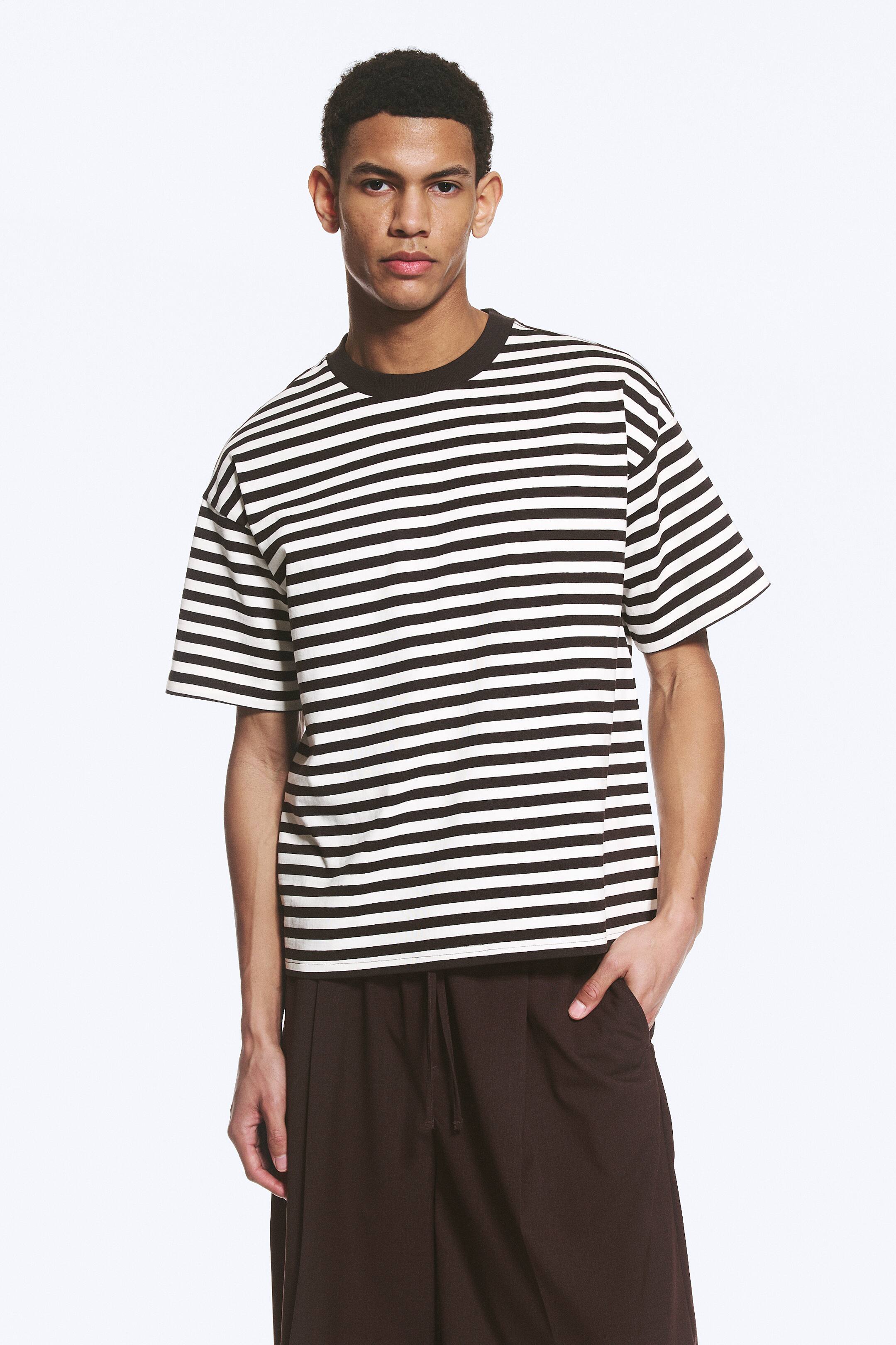 Visa större bild: En svart och vit horisontellt randig t-shirt visas framifrån, med en svart ribbad rund hals, korta ärmar och en avslappnad passform.