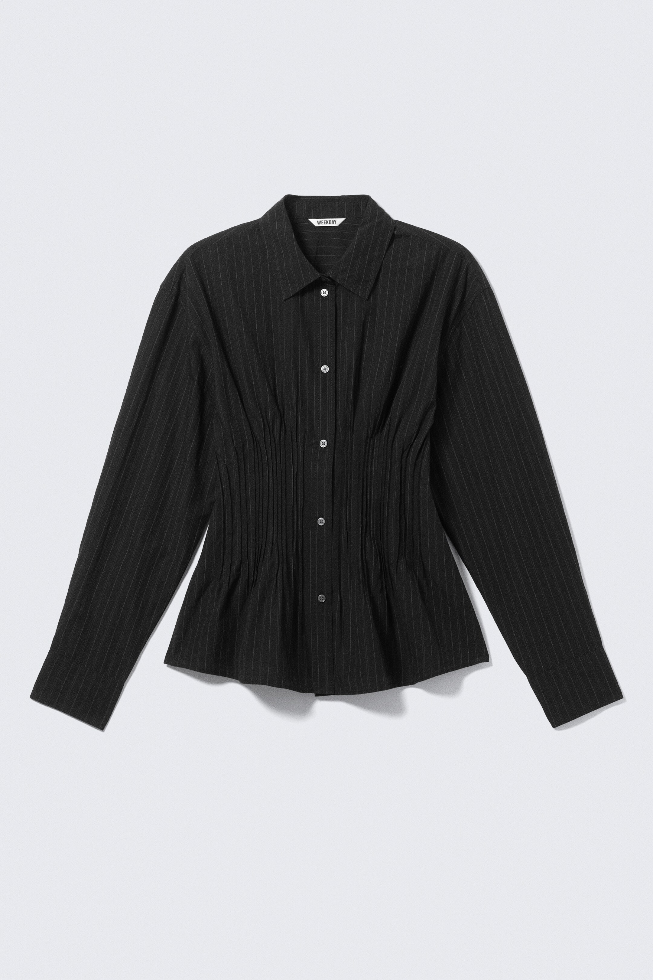 Ver imagen más grande: Una camisa negra de rayas finas está mostrando su PARTE FRONTAL, con un cuello en punta y un frente abotonado con botones de color claro. Está mostrando un detalle fruncido en la cintura, lo que crea una silueta entallada, junto con mangas largas, puños anchos y un dobladillo curvado.