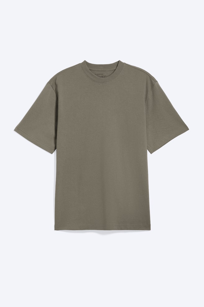 Luźny T-shirt w ciemnoszarym kolorze, widziany z przodu, z prÄ
żkowanym okrÄ
gÅym dekoltem, opuszczonÄ
liniÄ
ramion i szerokimi, krótkimi rÄkawami oraz prostym doÅem. - 1