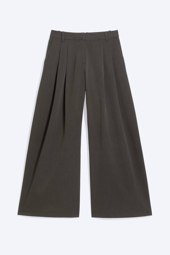Hellgraue Plisseehose mit niedriger Taille in einer frontalen Ansicht, mit weitem Bein und tiefen Bundfalten. Die Hose zeigt einen strukturierten Bund mit GÃ¼rtelschlaufen und dezenten Seitentaschen. - 1